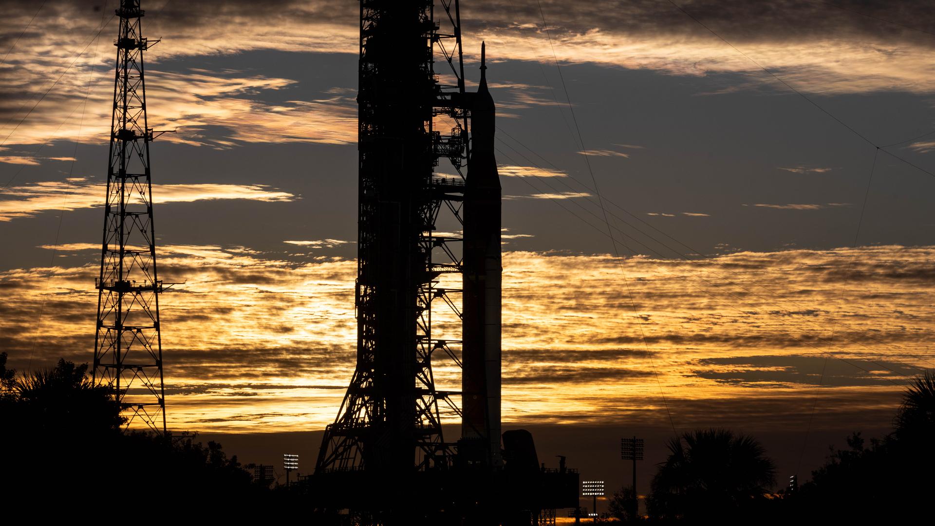 Clouds and the Sun illuminate the sky on Wednesday, Jan. 28, 2026, as NASA’s Artemis II SLS (Space Launch System) rocket and Orion spacecraft stand vertical at Launch Complex 39B at NASA’s Kennedy Space Center in Florida. The Artemis II test flight will take Commander Reid Wiseman, Pilot Victor Glover, and Mission Specialist Christina Koch from NASA and Mission Specialist Jeremy Hansen from the CSA (Canadian Space Agency), around the Moon and back to Earth no later than April 2026.