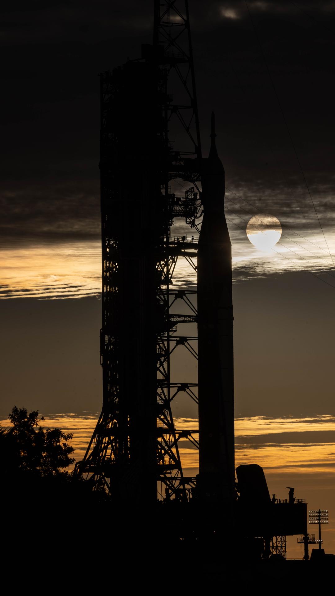 The sunrise peeks between NASA’s Artemis II SLS (Space Launch System) rocket with the Orion spacecraft atop and the mobile launcher at Launch Complex 39B at NASA’s Kennedy Space Center in Florida on Wednesday, Jan. 28, 2026. The Artemis II test flight will take Commander Reid Wiseman, Pilot Victor Glover, and Mission Specialist Christina Koch from NASA and Mission Specialist Jeremy Hansen from the CSA (Canadian Space Agency), around the Moon and back to Earth no later than April 2026.