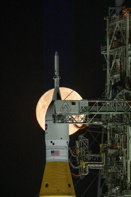 The Moon rises behind NASA’s Artemis II SLS (Space Launch System) rocket and ...