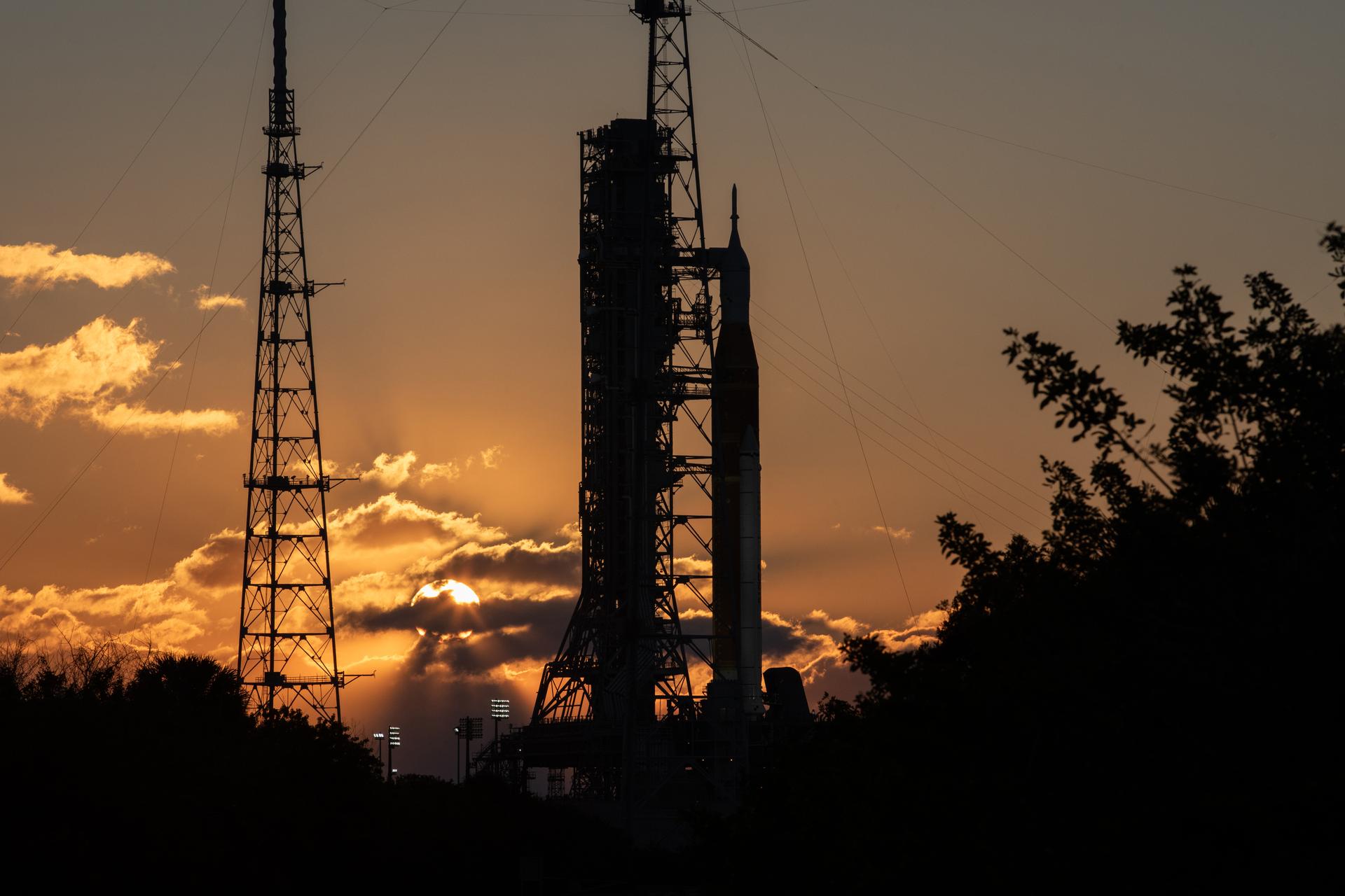 The Sun rises behind NASA’s Artemis II SLS (Space Launch System) rocket and Orion spacecraft atop a mobile launcher at Launch Complex 39B at NASA’s Kennedy Space Center in Florida on Sunday, Feb. 1, 2026. The Artemis II test flight will take Commander Reid Wiseman, Pilot Victor Glover, and Mission Specialist Christina Koch from NASA, and Mission Specialist Jeremy Hansen from the CSA (Canadian Space Agency), around the Moon and back to Earth.