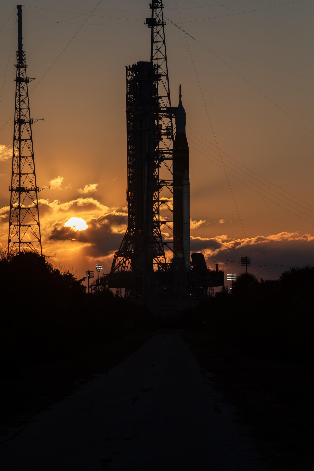 The Sun rises behind NASA’s Artemis II SLS (Space Launch System) rocket and Orion spacecraft atop a mobile launcher at Launch Complex 39B at NASA’s Kennedy Space Center in Florida on Sunday, Feb. 1, 2026. The Artemis II test flight will take Commander Reid Wiseman, Pilot Victor Glover, and Mission Specialist Christina Koch from NASA, and Mission Specialist Jeremy Hansen from the CSA (Canadian Space Agency), around the Moon and back to Earth.