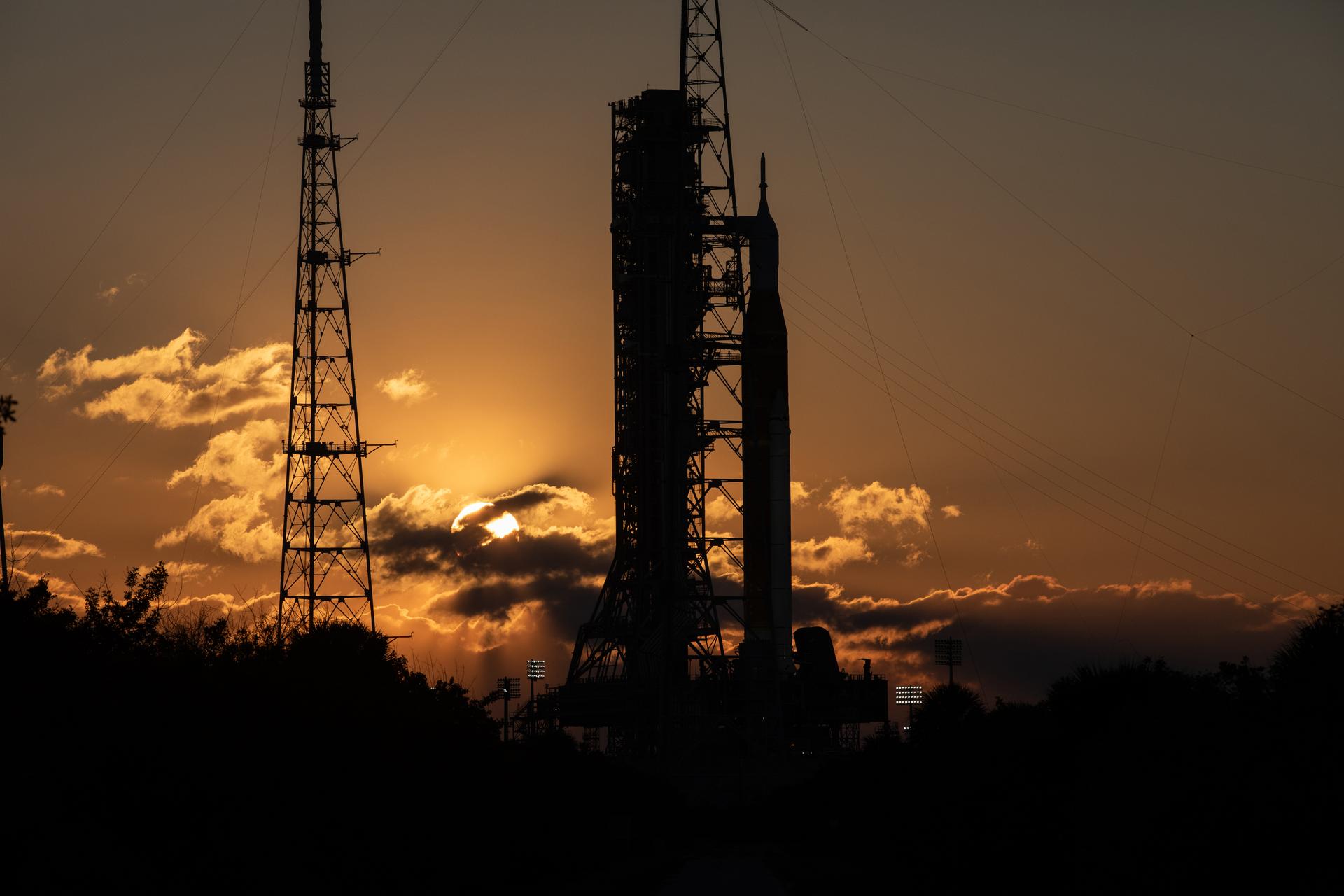 The Sun rises behind NASA’s Artemis II SLS (Space Launch System) rocket and Orion spacecraft atop a mobile launcher at Launch Complex 39B at NASA’s Kennedy Space Center in Florida on Sunday, Feb. 1, 2026. The Artemis II test flight will take Commander Reid Wiseman, Pilot Victor Glover, and Mission Specialist Christina Koch from NASA, and Mission Specialist Jeremy Hansen from the CSA (Canadian Space Agency), around the Moon and back to Earth.