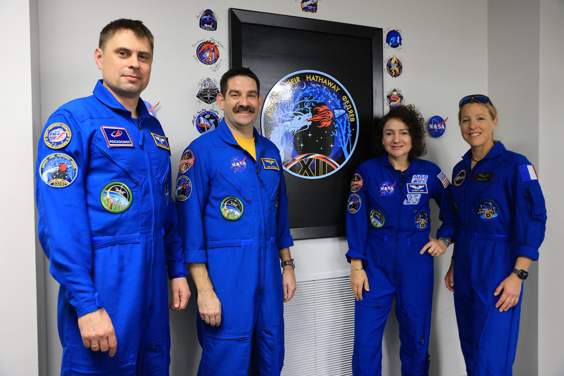 From left, Roscosmos cosmonaut Andrey Fedyaev, NASA astronauts Jack Hathaway and Jessica Meir, and ESA (European Space Agency) astronaut Sophie Adenot pose next to their mission insignia inside the Astronaut Crew Quarters in the Neil A. Armstrong Operations and Checkout Building at NASA’s Kennedy Space Center in Florida on Monday, Feb. 9, 2026. NASA’s SpaceX Crew-12 crew members will launch aboard a SpaceX Dragon spacecraft and Falcon 9 to the International Space Station no earlier than 5:15 a.m. EST on Friday, Feb. 13, from Cape Canaveral Space Force Station’s Space Launch Complex 40.