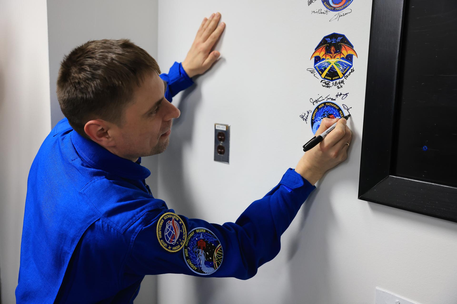 Roscosmos cosmonaut Andrey Fedyaev signs his name next to the Crew-12 mission insignia inside the Astronaut Crew Quarters in the Neil A. Armstrong Operations and Checkout Building at NASA’s Kennedy Space Center in Florida on Monday, Feb. 9, 2026, ahead of NASA’s SpaceX Crew-12 mission. A SpaceX Dragon spacecraft and Falcon 9 rocket will send Fedyaev, NASA astronauts Jessica Meir and Jack Hathaway, and ESA (European Space Agency) astronaut Sophie Adenot to the International Space Station no earlier than 5:15 a.m. EST on Friday, Feb. 13, from Cape Canaveral Space Force Station’s Space Launch Complex 40.