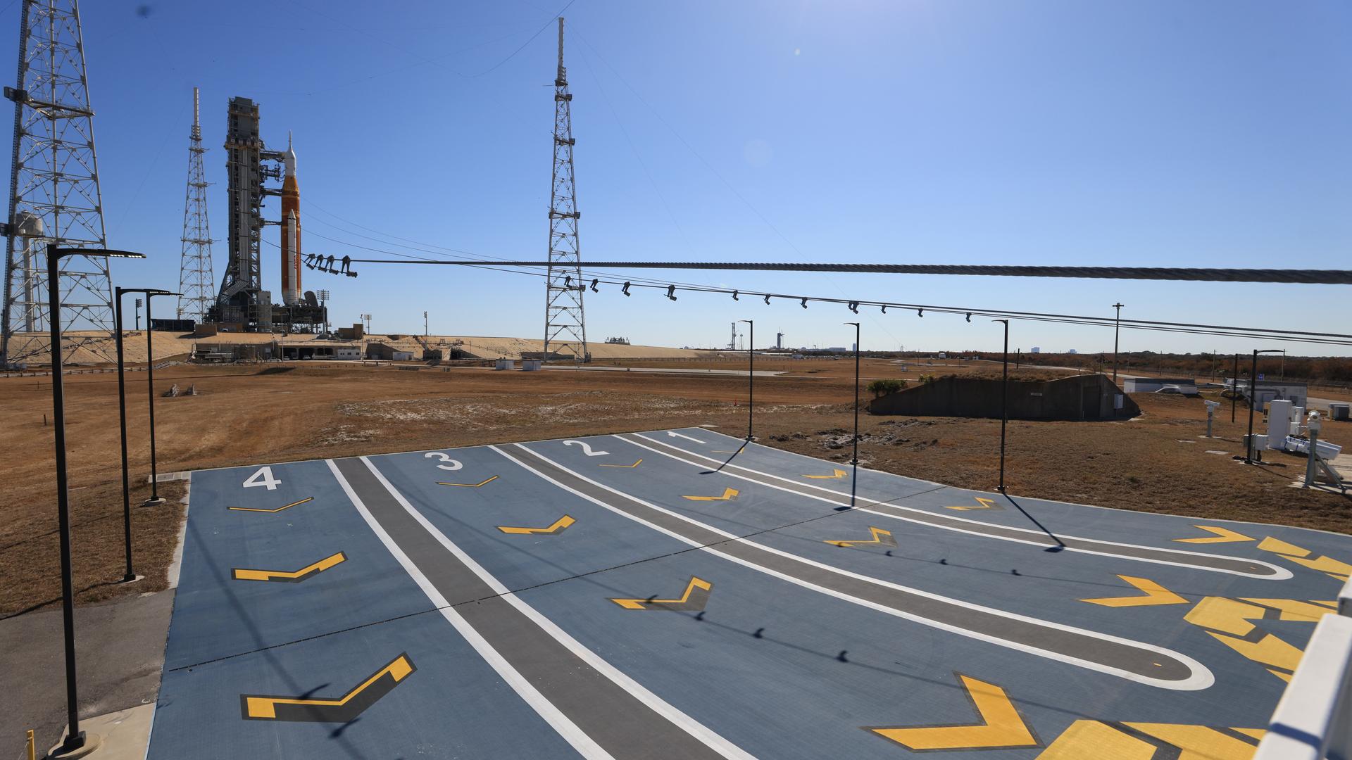 NASA’s Artemis II SLS (Space Launch System) rocket with the Orion spacecraft and launch abort system atop stands vertical in the background of the emergency egress system at Launch Complex 39B at NASA’s Kennedy Space Center in Florida on Tuesday, Feb. 10, 2026. The emergency egress system is an abort system for personnel to climb into four baskets of the mobile launcher to the base of the pad in the unlikely event of an emergency at the launch pad. The Artemis II test flight will take Commander Reid Wiseman, Pilot Victor Glover, and Mission Specialist Christina Koch from NASA, and Mission Specialist Jeremy Hansen from the CSA (Canadian Space Agency), around the Moon and back to Earth.