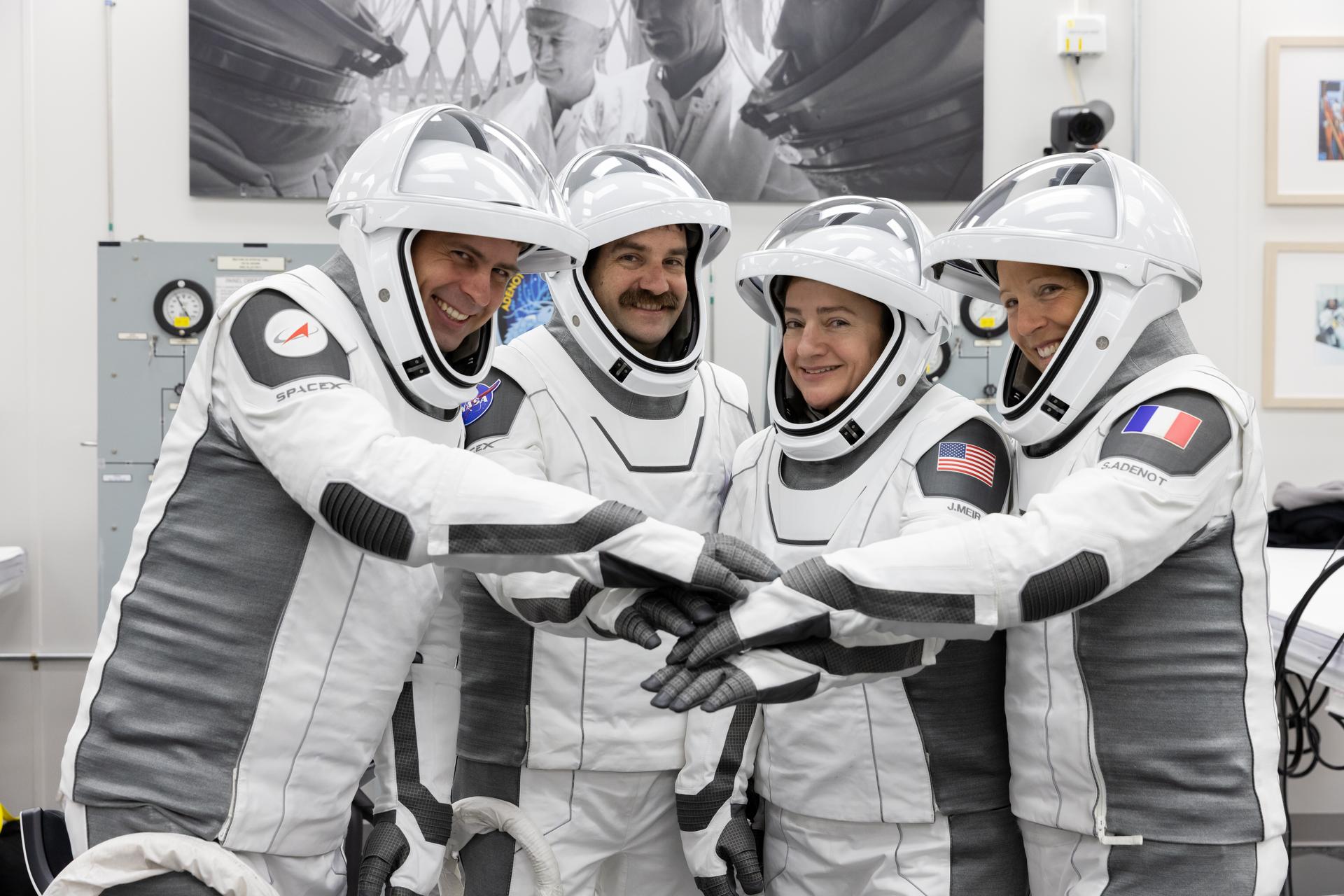 Image shows four astronauts in their white and black spacesuits stacking their hands in the middle before their launch to the International Space Station at 515 a.m. EST Friday, Feb. 13. Photo credit: NASA