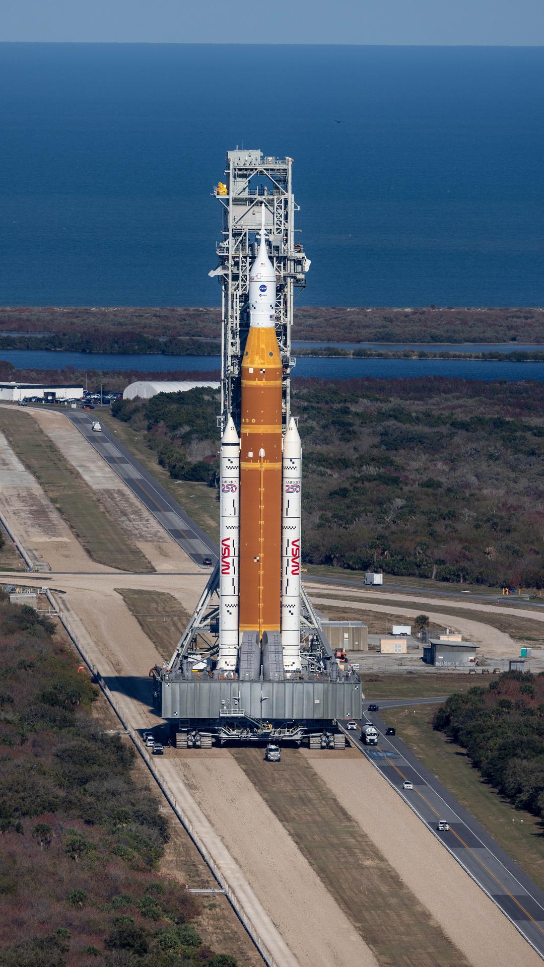 NASA’s crawler-transporter 2, carrying NASA’s Artemis II SLS (Space Launch System) rocket with the Orion spacecraft secured to mobile launcher 1, rolls back Wednesday, Feb. 25, 2026, to the Vehicle Assembly Building at NASA’s Kennedy Space Center in Florida to troubleshoot the flow of helium to the rocket’s upper stage, the interim cryogenic propulsion stage. Once complete, the SLS rocket will roll back to Launch Complex 39B to prepare to launch four astronauts around the Moon and back for the Artemis II test flight. 