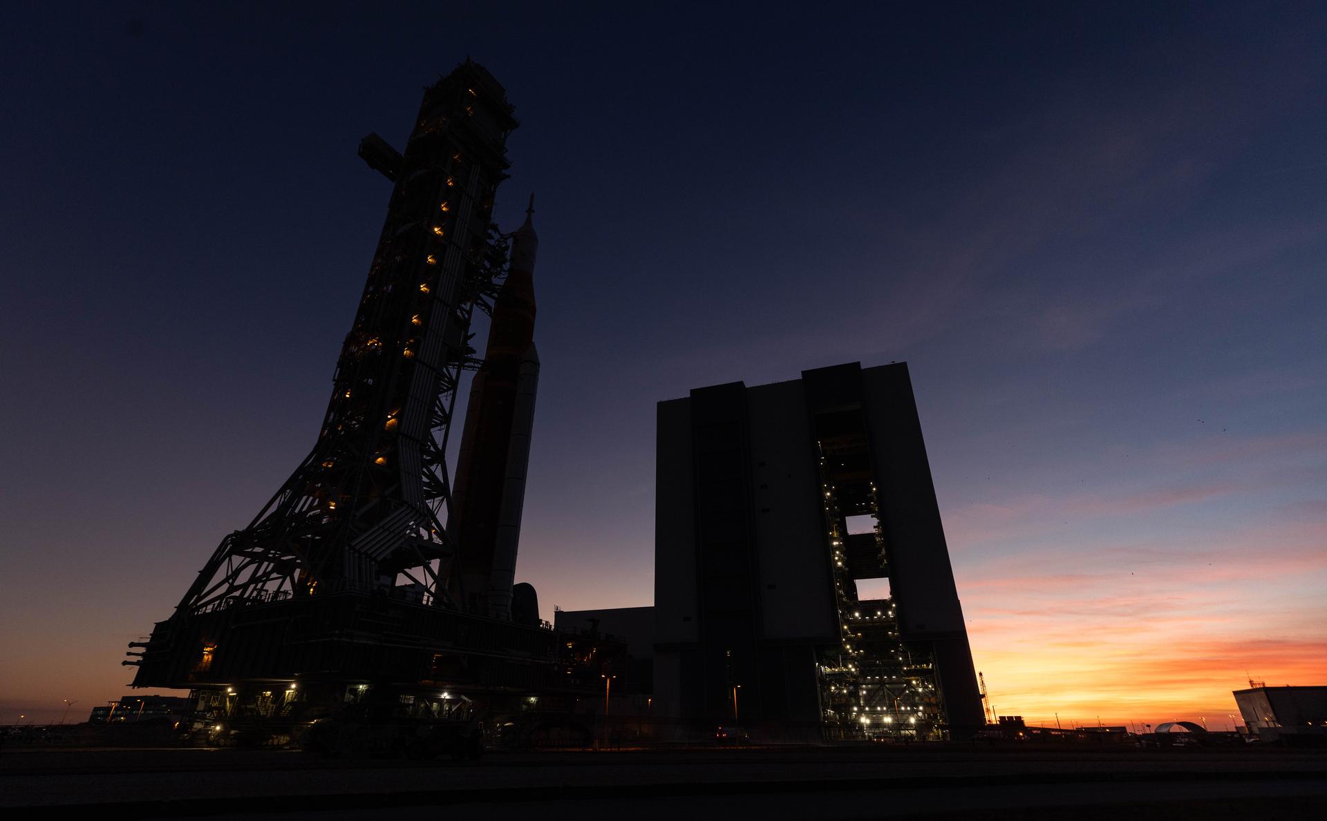 NASA’s crawler-transporter 2, carrying NASA’s Artemis II SLS (Space Launch System) rocket with the Orion spacecraft secured to mobile launcher 1, approaches the Vehicle Assembly Building at NASA’s Kennedy Space Center in Florida during the evening hours on Wednesday, Feb. 25, 2026, to troubleshoot the flow of helium to the rocket’s upper stage, the interim cryogenic propulsion stage. Once complete, the SLS rocket will roll back to Launch Complex 39B to prepare to launch four astronauts around the Moon and back for the Artemis II test flight. 