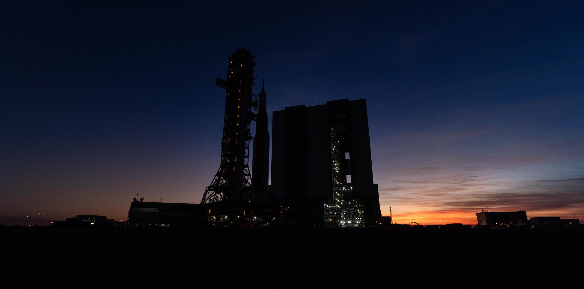 NASA’s crawler-transporter 2, carrying NASA’s Artemis II SLS (Space Launch System) rocket with the Orion spacecraft secured to mobile launcher 1, approaches the Vehicle Assembly Building at NASA’s Kennedy Space Center in Florida during the evening hours on Wednesday, Feb. 25, 2026, to troubleshoot the flow of helium to the rocket’s upper stage, the interim cryogenic propulsion stage. Once complete, the SLS rocket will roll back to Launch Complex 39B to prepare to launch four astronauts around the Moon and back for the Artemis II test flight. 