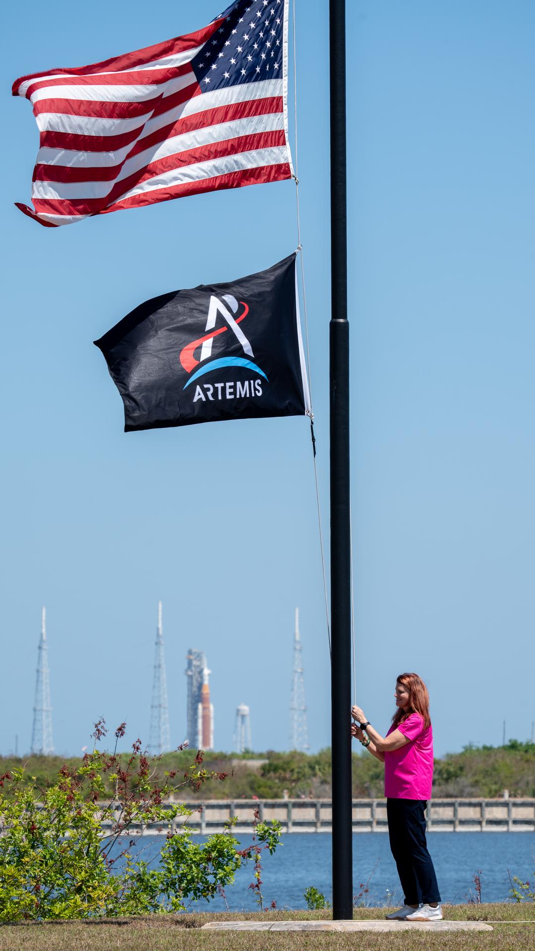 Charlie Blackwell-Thompson, Artemis II launch director raises the Artemis flag near the countdown clock at the NASA News Center at NASA’s Kennedy Space Center in Florida on Friday, March 27, 2026.  The Artemis II test flight mission will take Artemis II Commander Reid Wiseman, Pilot Victor Glover, and Mission Specialist Christina Koch from NASA, and Mission Specialist Jeremy Hansen from the CSA (Canadian Space Agency) on a 10-day journey around the Moon and back aboard NASA’s SLS (Space Launch System) rocket and Orion spacecraft from Launch Complex 39B no earlier than 6:24 p.m. EDT on Wednesday, April 1. 