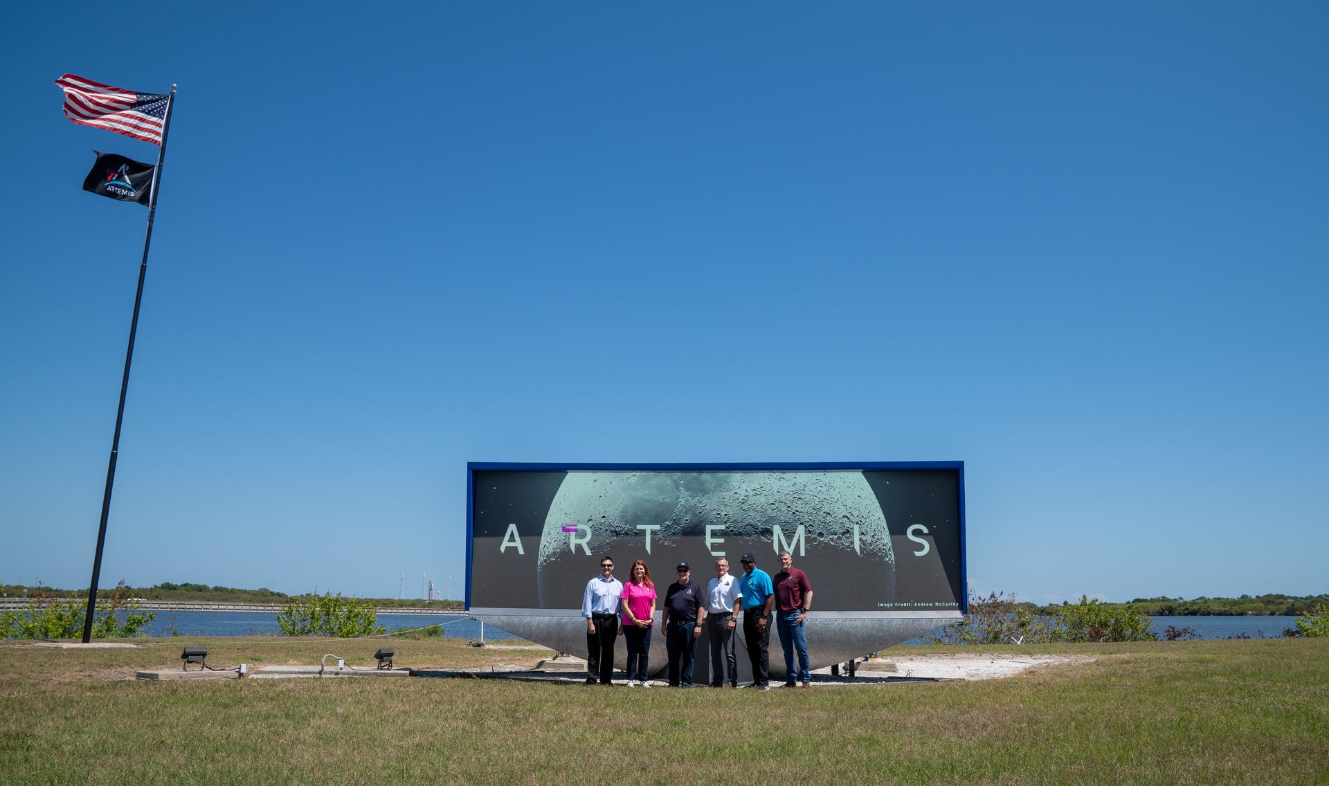 Robert Yaskovic, associate manager, Exploration Ground Systems Program; Charlie Blackwell-Thompson, Artemis II launch director; Shawn Quinn, manager, Exploration Ground Systems Program; Cliff Lanham, deputy manager, Exploration Ground Systems Program; NASA Kennedy Space Center Deputy Director Kelvin Manning; and Jeremy Graeber, assistant launch director, Exploration Ground Systems Program raise the Artemis flag near the countdown clock at the NASA News Center at NASA’s Kennedy Space Center in Florida on Friday, March 27, 2026.  The Artemis II test flight mission will take Artemis II Commander Reid Wiseman, Pilot Victor Glover, and Mission Specialist Christina Koch from NASA, and Mission Specialist Jeremy Hansen from the CSA (Canadian Space Agency) on a 10-day journey around the Moon and back aboard NASA’s SLS (Space Launch System) rocket and Orion spacecraft from Launch Complex 39B no earlier than 6:24 p.m. EDT on Wednesday, April 1. 