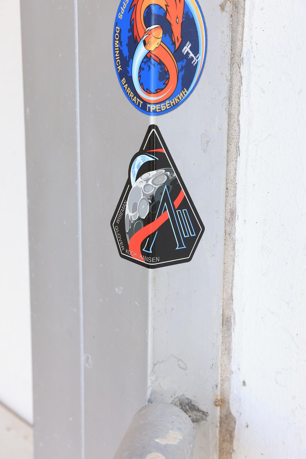 NASA’s Artemis II mission insignia is placed on the door underneath other mission insignias on the outside door the Neil A. Armstrong Operations and Checkout Building at NASA’s Kennedy Space Center in Florida on Monday, March 30, 2026. It’s a tradition for any crewed mission to place their insignias on the door leaving where they have quarantined and suited up ahead of launch. The Artemis II test flight mission will take the crew on a 10-day journey around the Moon and back aboard NASA’s SLS (Space Launch System) rocket and Orion spacecraft from Launch Complex 39B no earlier than 6:24 p.m. EDT on Wednesday, April 1. 