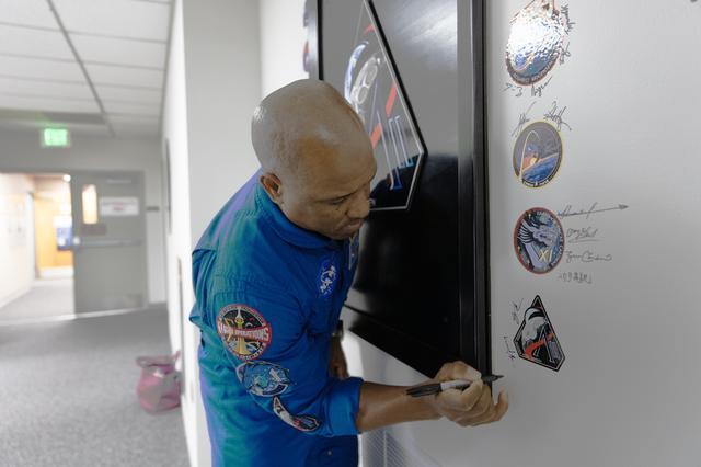 NASA astronaut Victor Glover, Artemis II pilot, signs his name on the Artemis...