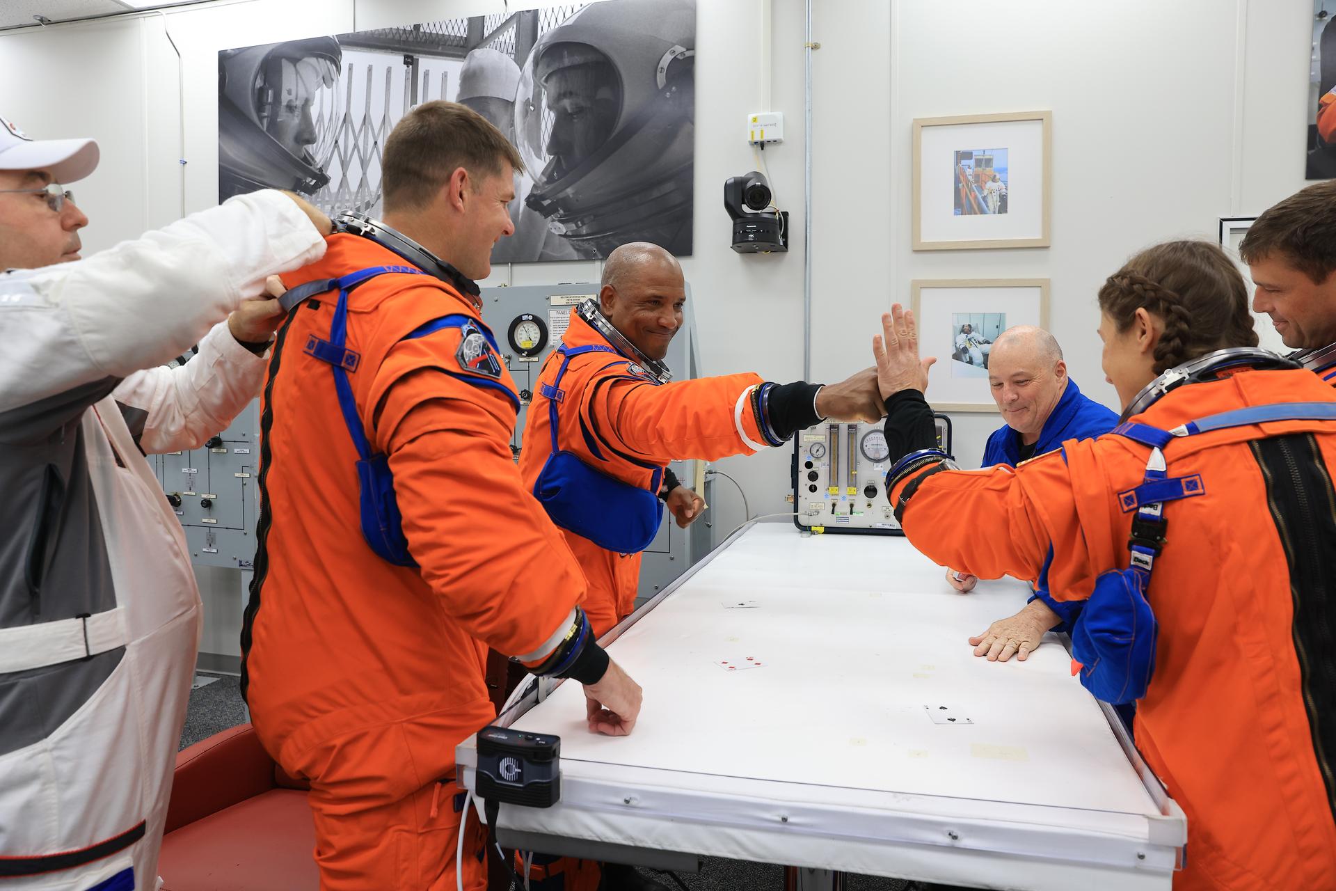 Artemis II crew members high-five after playing the traditional card game with NASA astronaut chief Scott Tingle, inside the Neil A. Armstrong Operations and Checkout Building at the agency’s Kennedy Space Center in Florida on Wednesday, April 1, 2026, ahead of the Artemis II test flight. The mission will take Artemis II Commander Reid Wiseman, Pilot Victor Glover, and Mission Specialist Christina Koch from NASA, along with Mission Specialist Jeremy Hansen from the CSA (Canadian Space Agency), on a 10-day journey around the Moon and back aboard NASA’s SLS (Space Launch System) rocket and Orion spacecraft with a two hour launch window opening at 6:24 p.m. EDT from Launch Complex 39B at NASA Kennedy. 