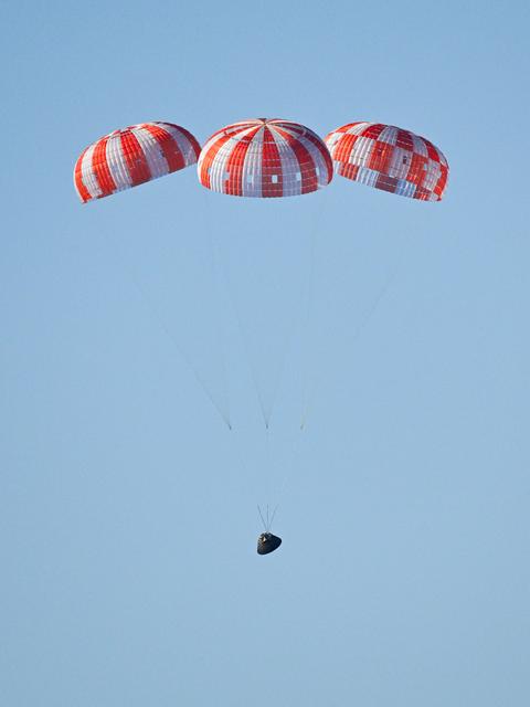 Parachutes secured to NASA’s Orion spacecraft deploy before splashdown in the...