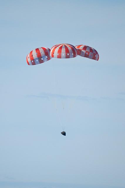 Parachutes secured to NASA’s Orion spacecraft deploy before splashdown in the...