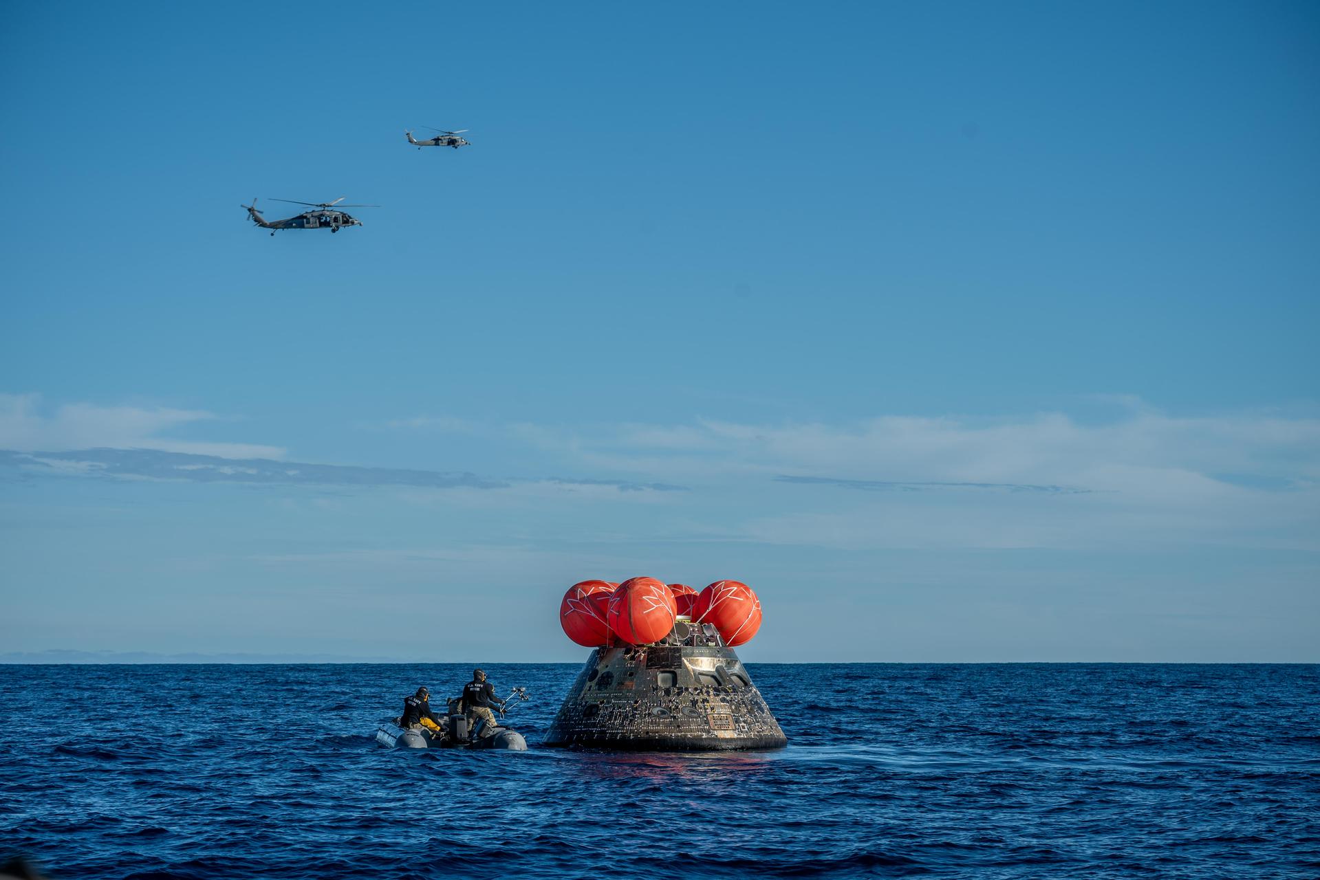 NASA's Orion spacecraft carrying Artemis II Commander Reid Wiseman, Pilot Victor Glover, and Mission Specialist Christina Koch from NASA, along with Mission Specialist Jeremy Hansen from the CSA (Canadian Space Agency), floats in the Pacific Ocean near San Diego, California, at 5:07 p.m. PDT, (8:07 p.m. EDT) on Friday, April 10, 2026. NASA’s Landing and Recovery team and U.S. Navy personnel aboard an inflatable raft and a H60-S Seahawk helicopter hovers above to communicate Orion’s location back to USS John P. Murtha to coordinate efforts to secure the spacecraft in the well deck of the ship. The Artemis II test flight launched on Wednesday, April 1, from NASA’s Kennedy Space Center in Florida to begin its 10-day journey around the Moon for scientific discovery, economic benefits, and to build on our foundation for the first crewed missions to Mars.