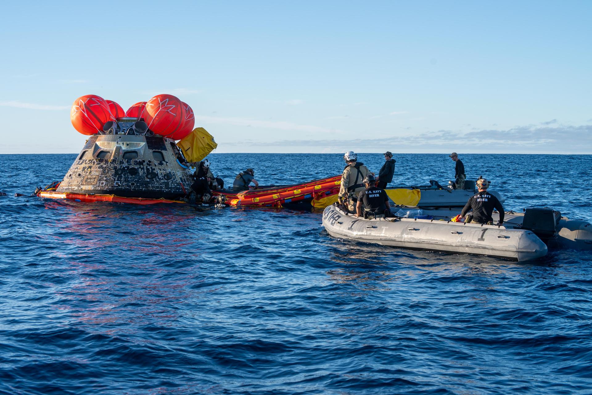 U.S. Navy personnel aboard an inflatable raft, called the front porch, help recover NASA's Orion spacecraft following its splashdown in the Pacific Ocean near San Diego, California, at 5:07 p.m. PDT, (8:07 p.m. EDT) on Friday, April 10, 2026, after the Artemis II test flight. The Artemis II mission carrying Artemis II Commander Reid Wiseman, Pilot Victor Glover, and Mission Specialist Christina Koch from NASA, along with Mission Specialist Jeremy Hansen from the CSA (Canadian Space Agency), launched on Wednesday, April 1, from NASA’s Kennedy Space Center in Florida to begin its 10-day journey around the Moon for scientific discovery, economic benefits, and to build on our foundation for the first crewed missions to Mars. NASA’s Landing and Recovery team and the U.S. Navy are coordinating efforts to secure Orion in the well deck of USS John P. Murtha. 