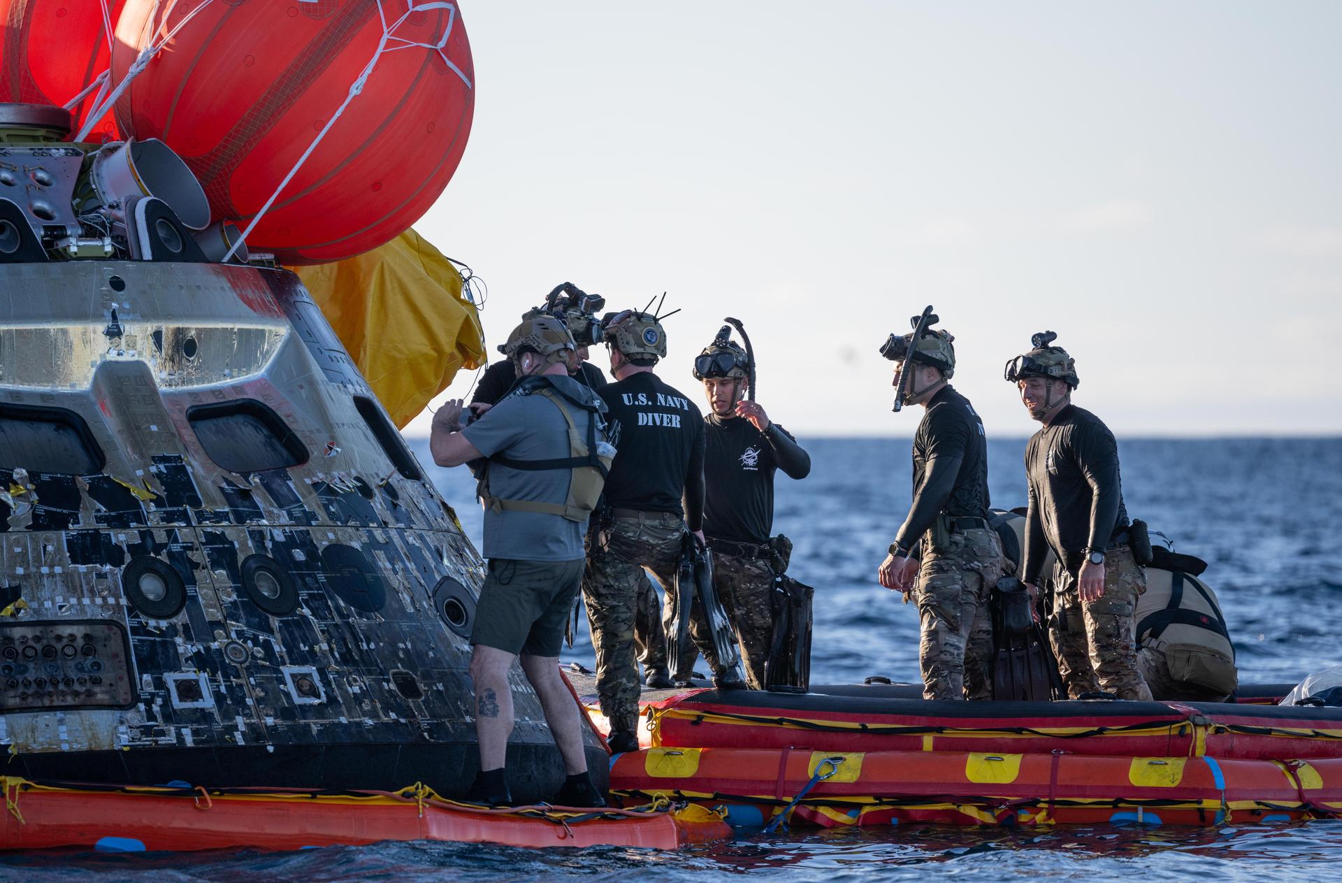 U.S. Navy personnel aboard an inflatable raft, called the front porch, help recover NASA's Orion spacecraft following its splashdown in the Pacific Ocean near San Diego, California, at 5:07 p.m. PDT, (8:07 p.m. EDT) on Friday, April 10, 2026, after the Artemis II test flight. The Artemis II mission carrying Artemis II Commander Reid Wiseman, Pilot Victor Glover, and Mission Specialist Christina Koch from NASA, along with Mission Specialist Jeremy Hansen from the CSA (Canadian Space Agency), launched on Wednesday, April 1, from NASA’s Kennedy Space Center in Florida to begin its 10-day journey around the Moon for scientific discovery, economic benefits, and to build on our foundation for the first crewed missions to Mars. NASA’s Landing and Recovery team and the U.S. Navy are coordinating efforts to secure Orion in the well deck of USS John P. Murtha. 