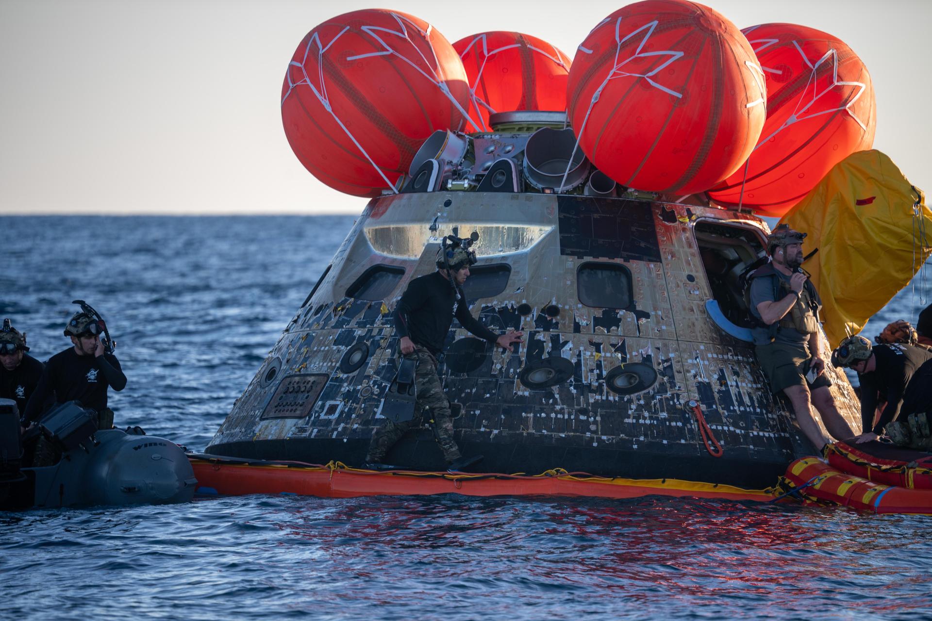 U.S. Navy personnel aboard an inflatable raft, called the front porch, help recover NASA's Orion spacecraft following its splashdown in the Pacific Ocean near San Diego, California, at 5:07 p.m. PDT, (8:07 p.m. EDT) on Friday, April 10, 2026, after the Artemis II test flight. The Artemis II mission carrying Artemis II Commander Reid Wiseman, Pilot Victor Glover, and Mission Specialist Christina Koch from NASA, along with Mission Specialist Jeremy Hansen from the CSA (Canadian Space Agency), launched on Wednesday, April 1, from NASA’s Kennedy Space Center in Florida to begin its 10-day journey around the Moon for scientific discovery, economic benefits, and to build on our foundation for the first crewed missions to Mars. NASA’s Landing and Recovery team and the U.S. Navy are coordinating efforts to secure Orion in the well deck of USS John P. Murtha.
