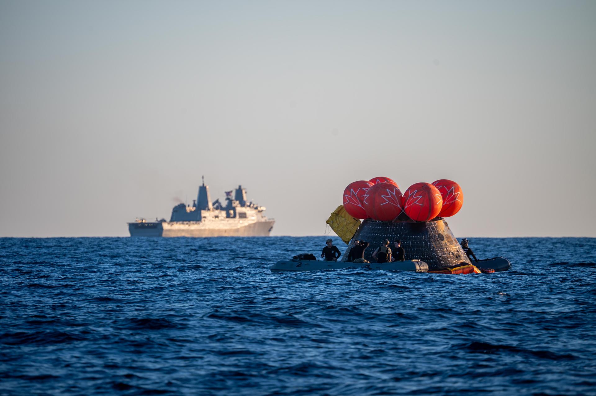 U.S. Navy personnel aboard an inflatable raft, called the front porch, help recover NASA's Orion spacecraft following its splashdown in the Pacific Ocean near San Diego, California, at 5:07 p.m. PDT, (8:07 p.m. EDT) on Friday, April 10, 2026, after the Artemis II test flight. The Artemis II mission carrying Artemis II Commander Reid Wiseman, Pilot Victor Glover, and Mission Specialist Christina Koch from NASA, along with Mission Specialist Jeremy Hansen from the CSA (Canadian Space Agency), launched on Wednesday, April 1, from NASA’s Kennedy Space Center in Florida to begin its 10-day journey around the Moon for scientific discovery, economic benefits, and to build on our foundation for the first crewed missions to Mars. NASA’s Landing and Recovery team and the U.S. Navy are coordinating efforts to secure Orion in the well deck of USS John P. Murtha.