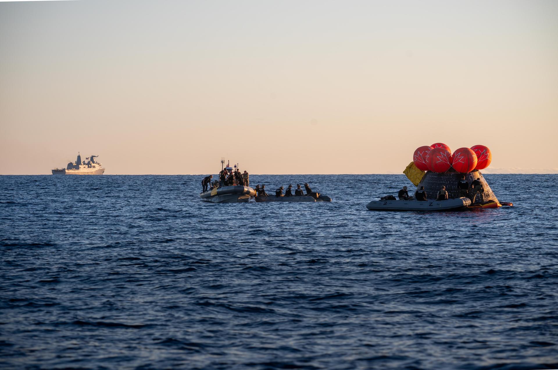 U.S. Navy personnel aboard an inflatable raft, called the front porch, help recover NASA's Orion spacecraft following its splashdown in the Pacific Ocean near San Diego, California, at 5:07 p.m. PDT, (8:07 p.m. EDT) on Friday, April 10, 2026, after the Artemis II test flight. The Artemis II mission carrying Artemis II Commander Reid Wiseman, Pilot Victor Glover, and Mission Specialist Christina Koch from NASA, along with Mission Specialist Jeremy Hansen from the CSA (Canadian Space Agency), launched on Wednesday, April 1, from NASA’s Kennedy Space Center in Florida to begin its 10-day journey around the Moon for scientific discovery, economic benefits, and to build on our foundation for the first crewed missions to Mars. NASA’s Landing and Recovery team and the U.S. Navy are coordinating efforts to secure Orion in the well deck of USS John P. Murtha.
