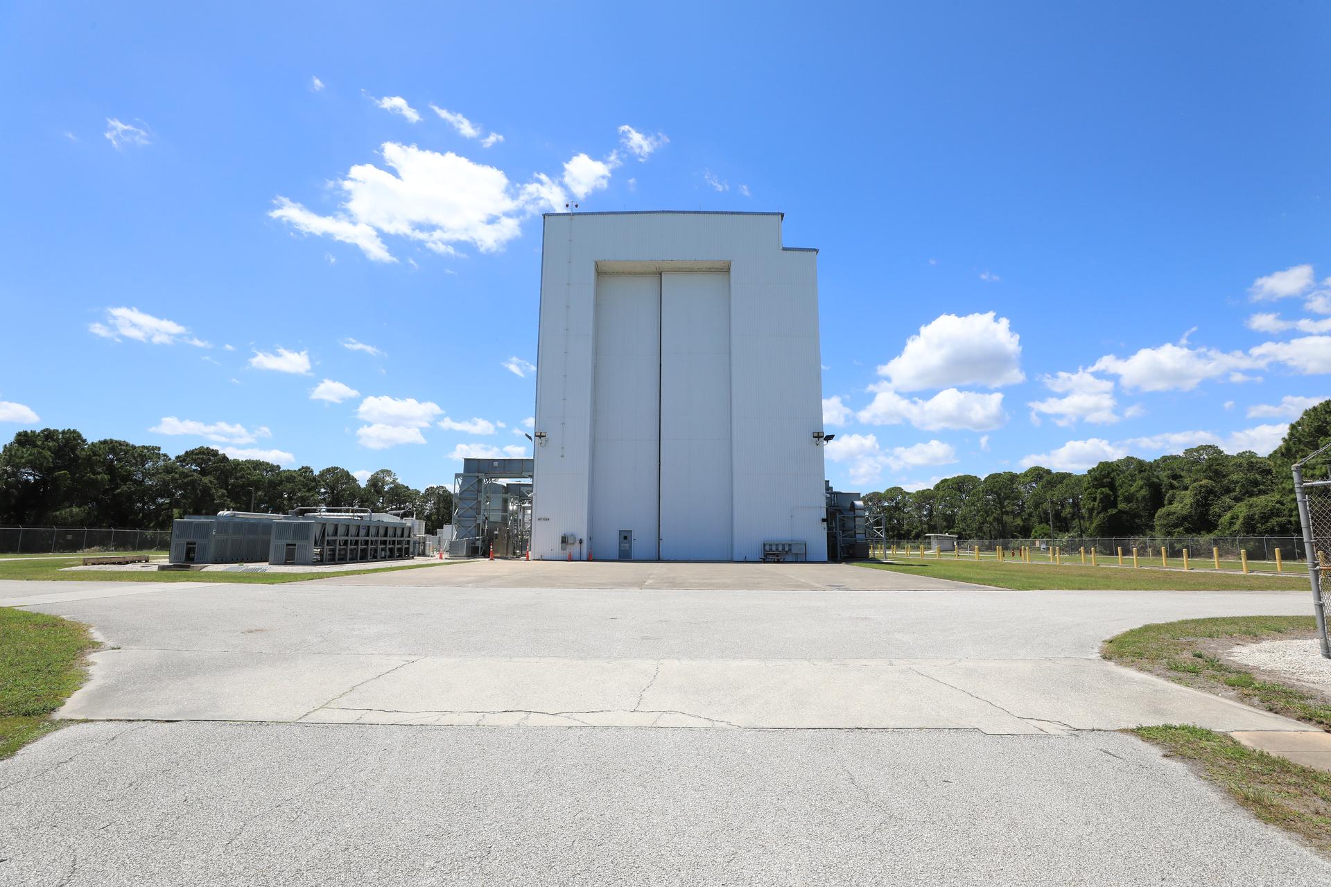 A photograph shows the exterior of NASA’s Payload Hazardous Servicing Facility (PHSF) on Tuesday, April 21, 2026, at NASA’s Kennedy Space Center in Florida. Recently, technicians performed several upgrades to the facility ahead of the arrival of the agency’s Nancy Grace Roman Space Telescope, designed to provide deep, panoramic views of the cosmos, generating never-before-seen pictures that will revolutionize our understanding of the universe. Roman will undergo several prelaunch operations, including thermal protection closeout, cleaning, solar array work, and loading hydrazine propellant. The PHSF is one of the very few facilities where spacecraft undergo both hazardous fueling operations and delicate contamination control procedures. 