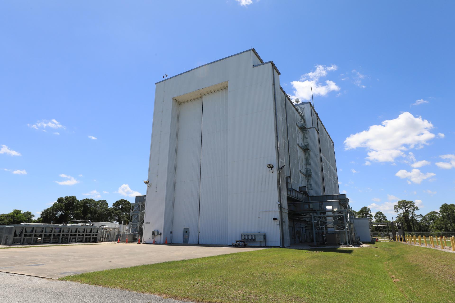 A photograph shows the exterior of NASA’s Payload Hazardous Servicing Facility (PHSF) on Tuesday, April 21, 2026, at NASA’s Kennedy Space Center in Florida. Recently, technicians performed several upgrades to the facility ahead of the arrival of the agency’s Nancy Grace Roman Space Telescope, designed to provide deep, panoramic views of the cosmos, generating never-before-seen pictures that will revolutionize our understanding of the universe. Roman will undergo several prelaunch operations, including thermal protection closeout, cleaning, solar array work, and loading hydrazine propellant. The PHSF is one of the very few facilities where spacecraft undergo both hazardous fueling operations and delicate contamination control procedures. 