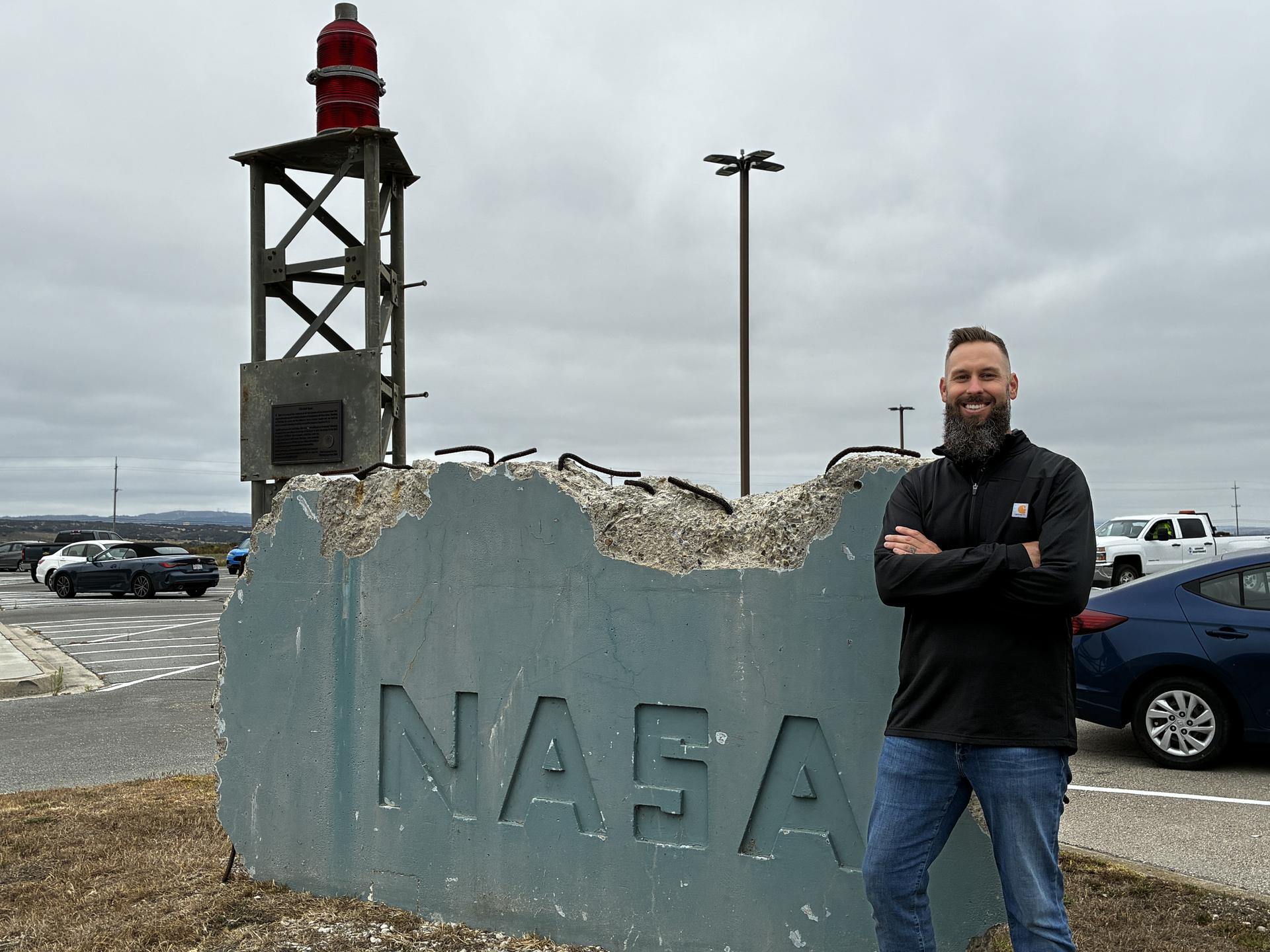 At Vandenberg Space Force Base in California, NASA employee Eric Fernandez stands by a preserved concrete section from the Space Launch Complex2 Mobile Service Tower counterweight, saved during demolition to retain the NASA insignia. The artifact was part of Delta and Delta II launches for decades before demolition, with its last launch for the agency being NASA’s ICESat2 on Sept. 15, 2018.