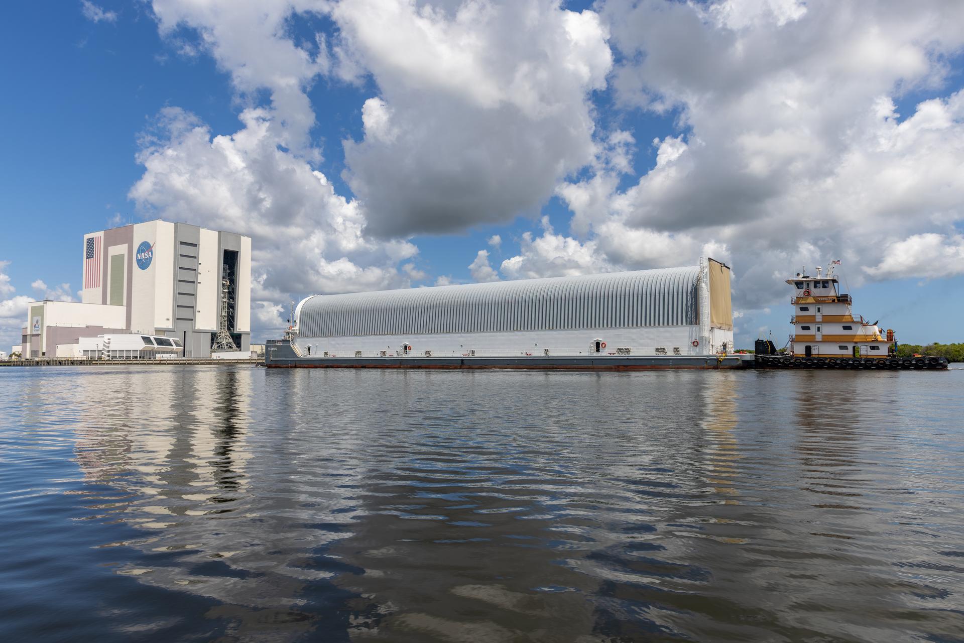 NASA’s Pegasus barge arrives at the Launch Complex 39 turn basin at the agency’s Kennedy Space Center in Florida carrying NASA’s Nancy Grace Roman Space Telescope on Sunday, June 21, 2026. Teams will offload and transport the observatory to the spaceport’s Payload Hazardous Servicing Facility where it will undergo processing ahead of launch, targeted no earlier than Sunday, Aug. 30, 2026. Named for NASA’s first chief astronomer and “mother of the Hubble Space Telescope,” Roman will offer a field of view over 100 times larger than Hubble’s to study up to a billion galaxies, directly image exoplanets and planet forming disks, and address fundamental questions about dark energy, exoplanets, and infrared astrophysics.
