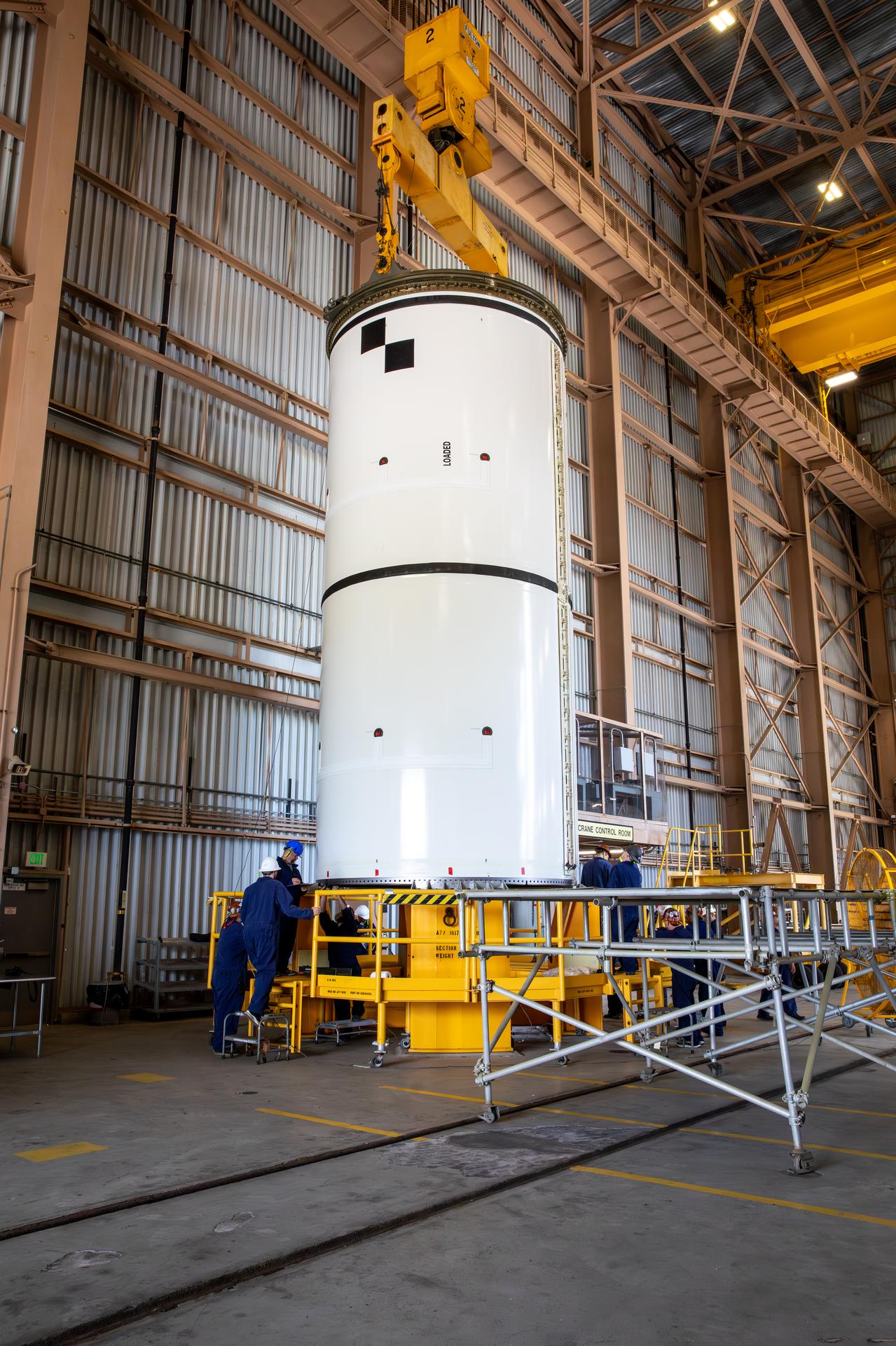 The left-hand forward solid rocket booster segment for NASA’s Artemis III SLS (Space Launch System) rocket is offloaded from its rail car transportation container and inspected ahead of processing inside the Rotation, Processing and Surge Facility at the agency’s Kennedy Space Center in Florida on Tuesday, June 30, 2026. The SLS rocket’s twin boosters, manufactured by Northrop Grumman in Utah, will provide more than 75 percent of the SLS rocket’s total thrust at launch. The Artemis III mission will launch crew in the Orion spacecraft on top of the SLS rocket to test rendezvous and docking capabilities between Orion and commercial spacecraft needed to land astronauts on the Moon.