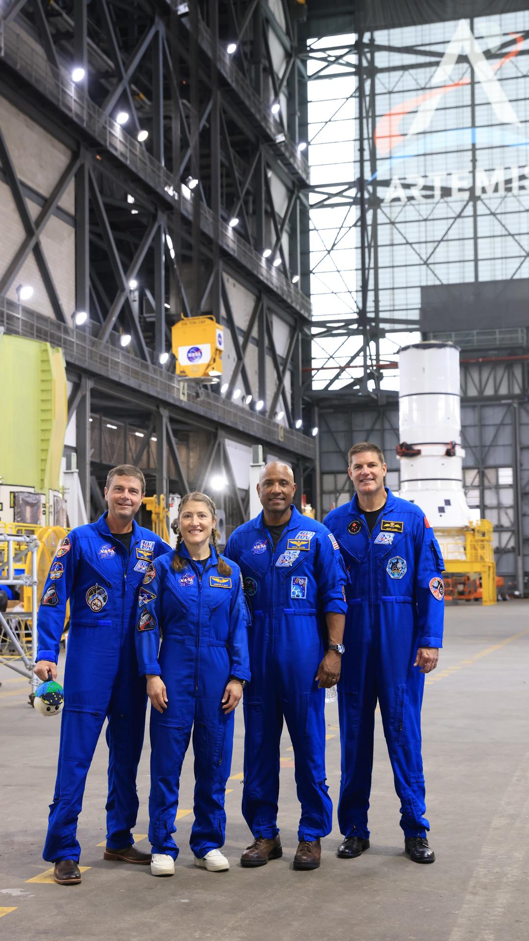 From left, Artemis II crew NASA astronauts Reid Wiseman, Christina Koch, and Victor Glover, along with CSA (Canadian Space Agency) astronaut Jeremy Hansen pose for a photograph inside the Vehicle Assembly Building at NASA’s Kennedy Space Center in Florida on Tuesday, July 7, 2026, with the Artemis III left-hand aft assembly solid rocket booster segment behind them in the transfer aisle. The crew returned to NASA Kennedy for their first official visit since launch of Artemis II on Wednesday, April 1, 2026, to visit with the center’s workforce and tour facilities to view progress on Artemis III prelaunch processing.