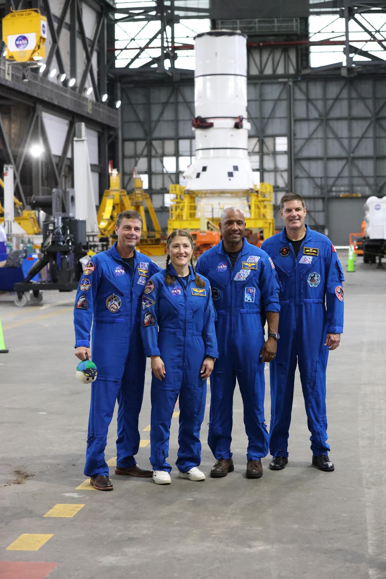 From left, Artemis II crew NASA astronauts Reid Wiseman, Christina Koch, and Victor Glover, along with CSA (Canadian Space Agency) astronaut Jeremy Hansen pose for a photograph inside the Vehicle Assembly Building at NASA’s Kennedy Space Center in Florida on Tuesday, July 7, 2026, with the Artemis III left-hand aft assembly solid rocket booster segment behind them in the transfer aisle. The crew returned to NASA Kennedy for their first official visit since launch of Artemis II on Wednesday, April 1, 2026, to visit with the center’s workforce and tour facilities to view progress on Artemis III prelaunch processing.