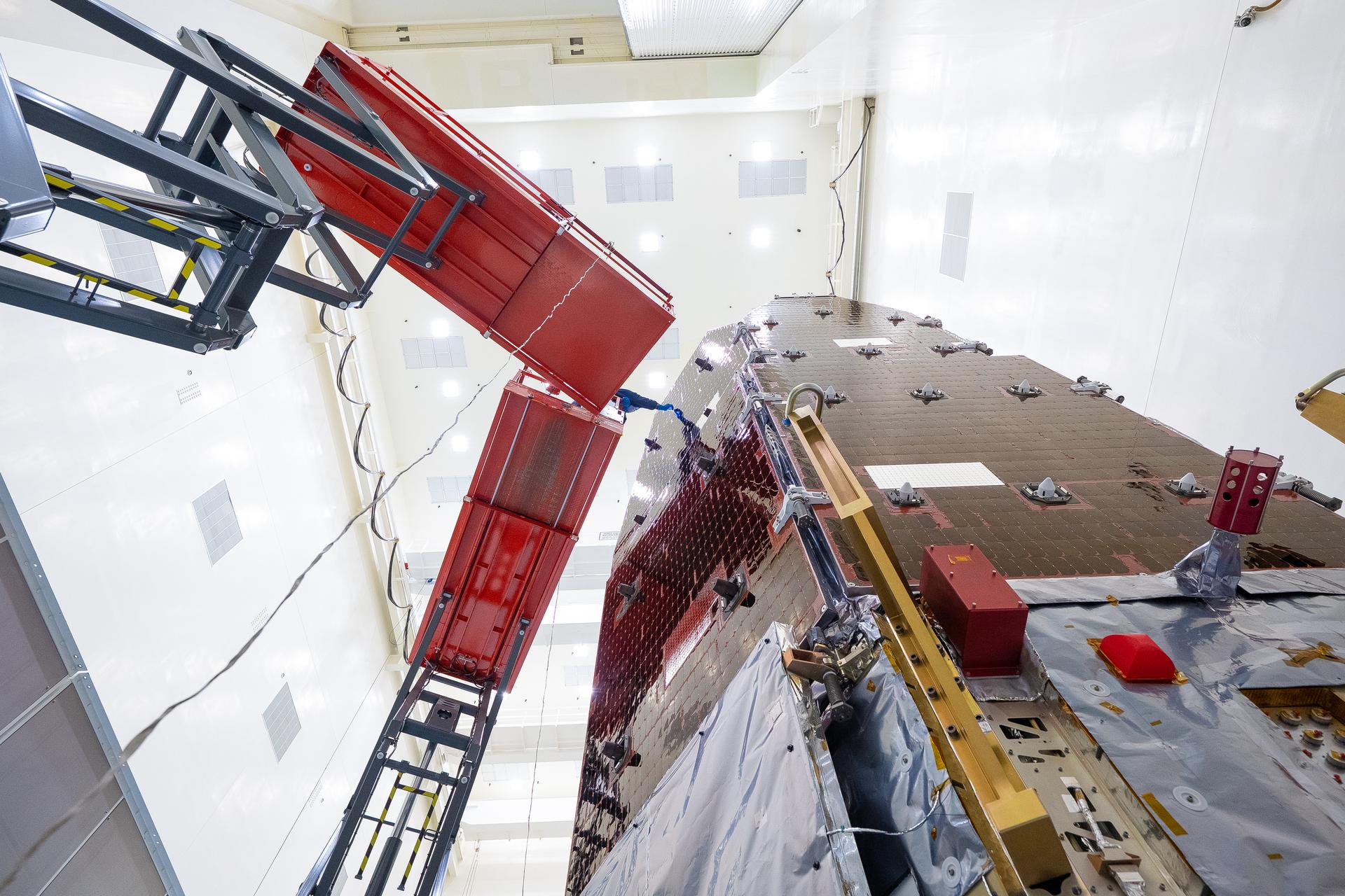 Technicians and engineers inside the Payload Hazardous Servicing Facility at NASA’s Kennedy Space Center in Florida clean and inspect the Solar Array Sun Shield (SASS) on the agency’s Nancy Grace Roman Space Telescope on Wednesday, July 8, 2026. The SASS is made up of six solar array panels, with the two center panels fixed while the four outer ones are deployed once in orbit. The Roman team will orient the SASS toward the Sun to provide power to the entire observatory and shade the telescope and instruments beneath. NASA designed this flagship mission to help astronomers explore dark matter, dark energy, and exoplanets.