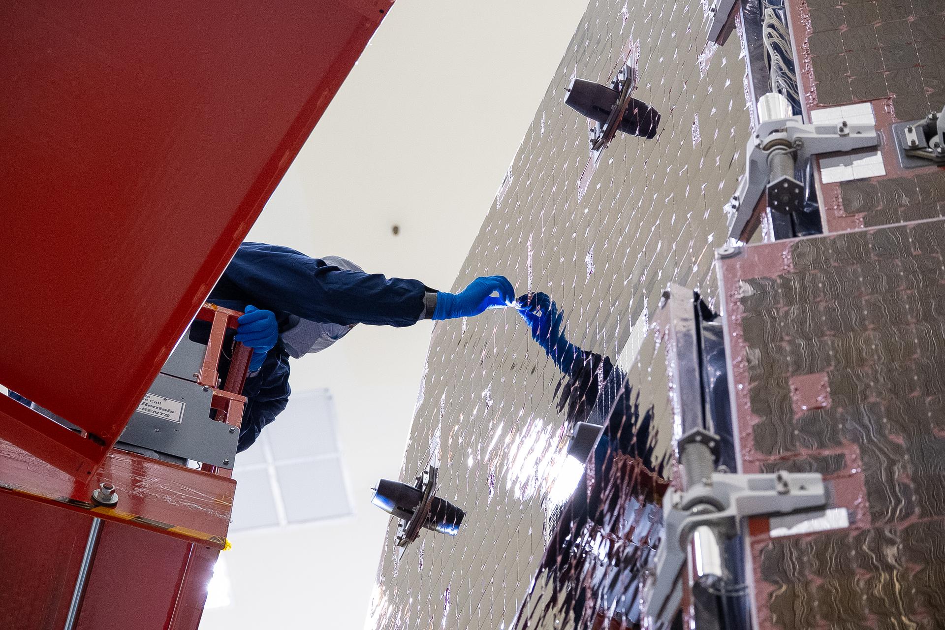 Technicians and engineers inside the Payload Hazardous Servicing Facility at NASA’s Kennedy Space Center in Florida clean and inspect the Solar Array Sun Shield (SASS) on the agency’s Nancy Grace Roman Space Telescope on Wednesday, July 8, 2026. The SASS is made up of six solar array panels, with the two center panels fixed while the four outer ones are deployed once in orbit. The Roman team will orient the SASS toward the Sun to provide power to the entire observatory and shade the telescope and instruments beneath. NASA designed this flagship mission to help astronomers explore dark matter, dark energy, and exoplanets.