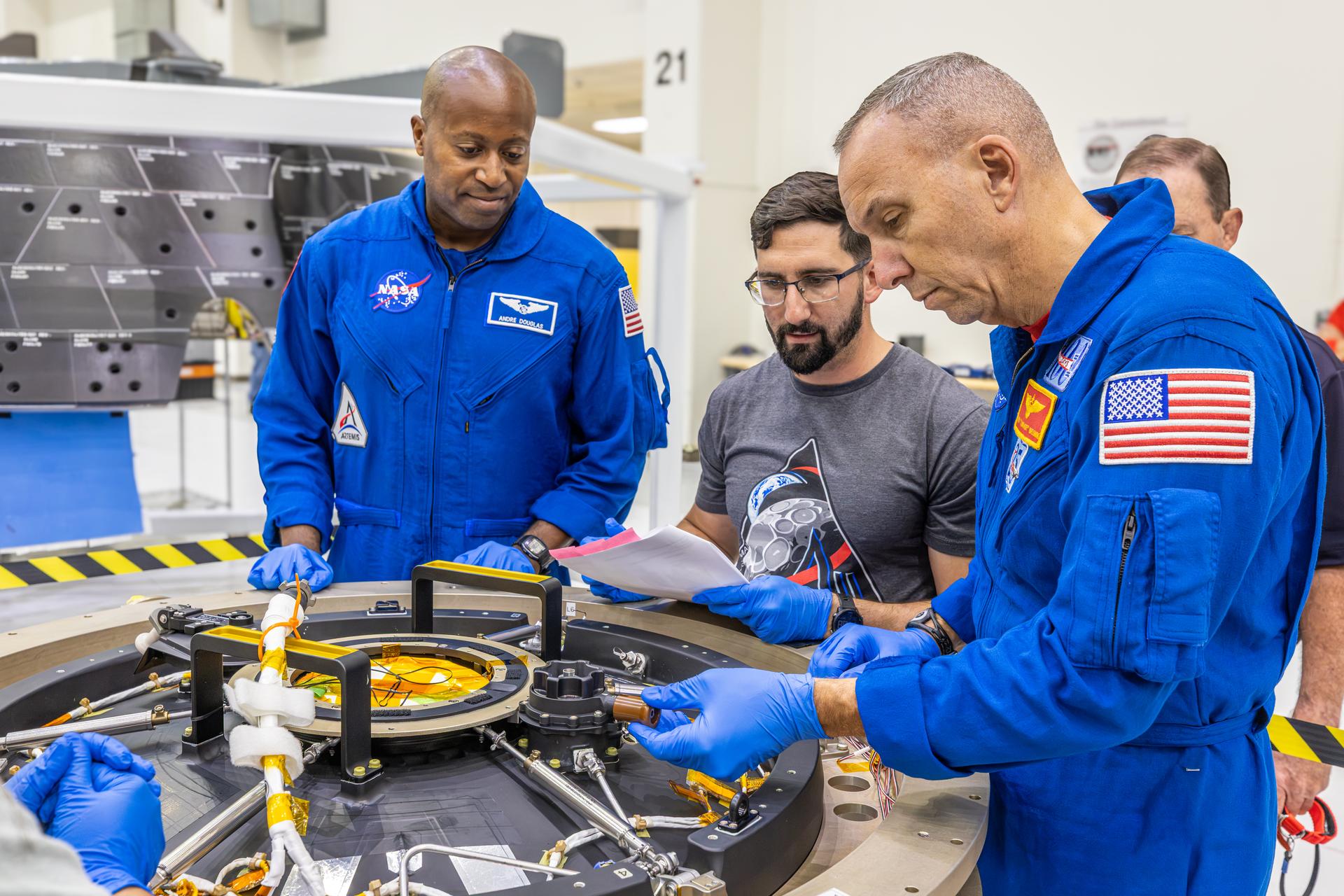 Artemis III crew members, NASA astronauts Randy Bresnick (right) and Andre Douglas (left), learn more about Orion spacecraft hardware with teams inside the high bay of the Neil A. Armstrong Operations and Checkout Building at NASA’s Kennedy Space Center in Florida on Friday, July 10, 2026. The astronauts met with Orion teams and got a close look at the work underway for their upcoming mission. Bresnick, Douglas, NASA astronaut Frank Rubio, and ESA (European Space Agency) astronaut Luca Parmitano will launch on the Artemis III mission to conduct critical rendezvous and docking tests with lunar lander systems in low Earth orbit, advancing the capabilities needed before astronauts return to the lunar surface on Artemis IV.