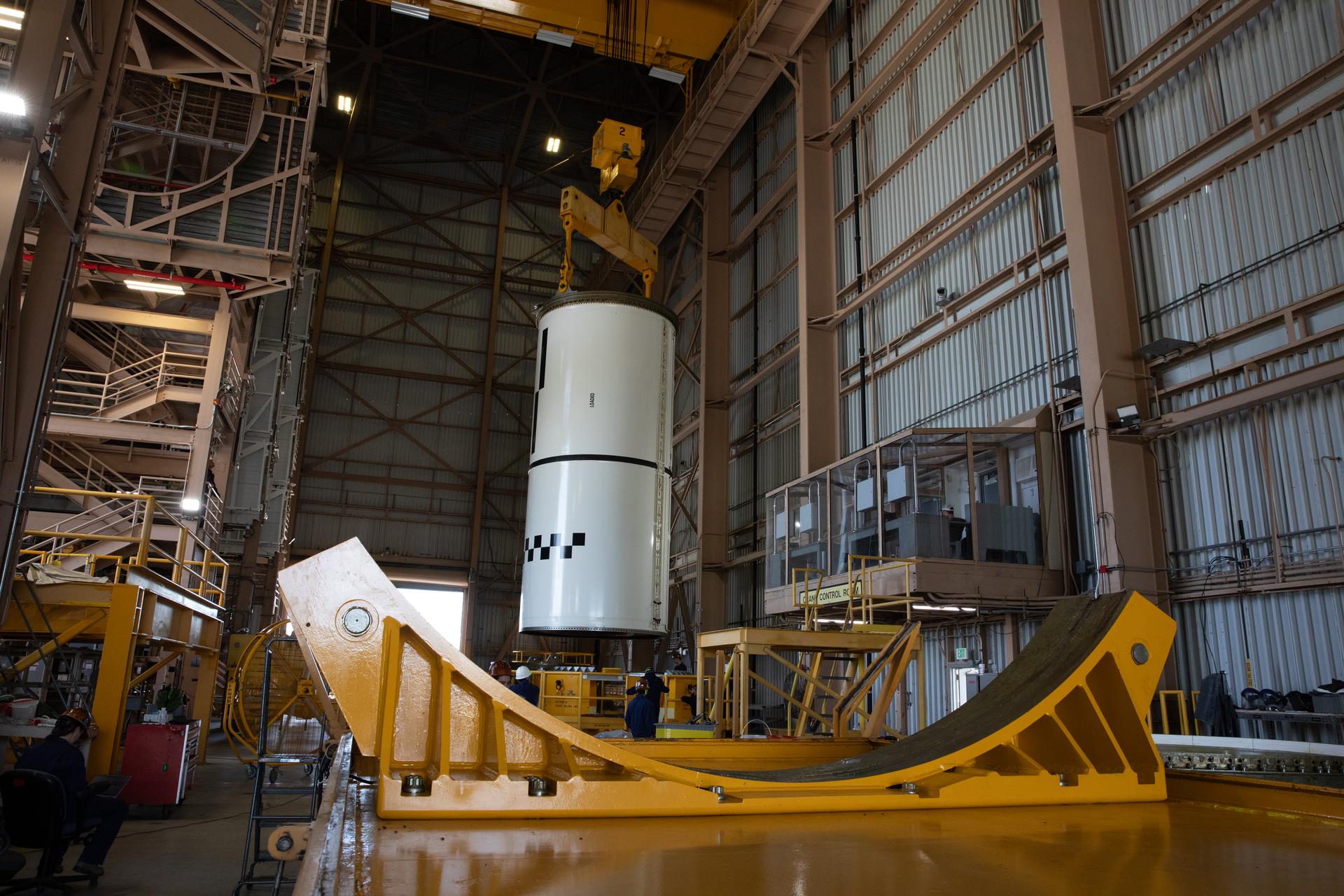From left, Kat Ternus, NASA handling engineer at NASA’s Kennedy Space Center in Florida, and other technicians use a massive crane to transport the right-hand forward center assembly solid rocket booster segment for the Artemis III SLS (Space Launch System) rocket inside the Rotation, Processing, and Surge Facility at NASA’s Kennedy Space Center in Florida on Tuesday, July 14, 2026. The twin boosters, manufactured by Northrop Grumman in Utah, will provide more than 75 percent of the SLS rocket’s total thrust at launch. The Artemis III mission will launch astronauts in the Orion spacecraft on top of the SLS rocket to test rendezvous and docking capabilities between Orion and commercial spacecraft needed to land astronauts on the Moon.