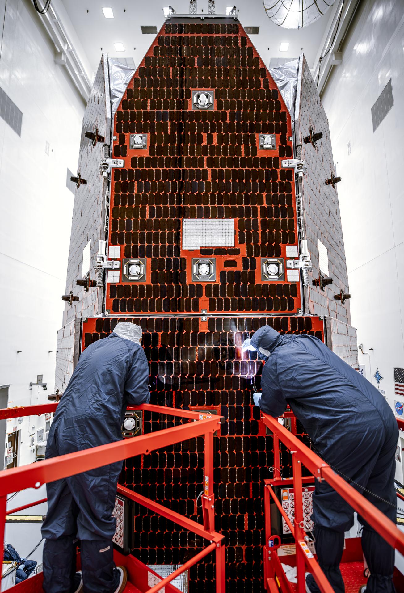 Technicians and engineers inside the Payload Hazardous Servicing Facility at NASA’s Kennedy Space Center in Florida clean and inspect the Solar Array Sun Shield (SASS) on the agency’s Nancy Grace Roman Space Telescope on Tuesday, July 14, 2026. The SASS is made up of six solar array panels, with the two center panels fixed while the four outer ones are deployed once in orbit. The Roman team will orient the SASS toward the Sun to provide power to the entire observatory and shade the telescope and instruments beneath. NASA designed this flagship mission to help astronomers explore dark matter, dark energy, and exoplanets.