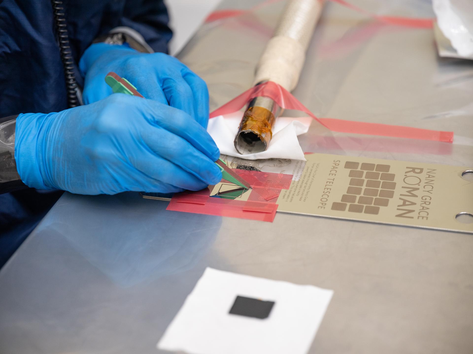 A technician inside the Payload Hazardous Servicing Facility at NASA’s Kennedy Space Center in Florida installs a memory card containing a total of 1,350,144 names as part of a commemorative plaque on the Nancy Grace Roman Space Telescope on Friday, July 17, 2026. The names, submitted by people from across the globe, including astronauts from NASA’s Artemis II and Artemis III missions, will travel with the Roman observatory to the Sun-Earth Lagrange point 2, or L2, about one million miles from Earth, where the Sun’s and Earth’s gravity balance out. Roman is named after Dr. Nancy Grace Roman, NASA’s first chief astronomer and one of the architects of the agency’s modern science program.