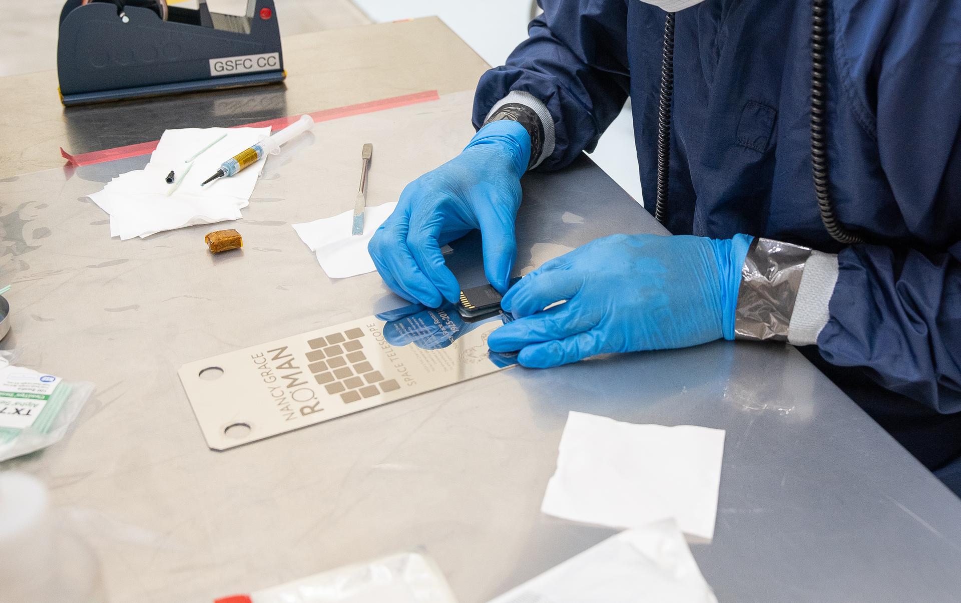 A technician inside the Payload Hazardous Servicing Facility at NASA’s Kennedy Space Center in Florida installs a memory card containing a total of 1,350,144 names as part of a commemorative plaque on the Nancy Grace Roman Space Telescope on Friday, July 17, 2026. The names, submitted by people from across the globe, including astronauts from NASA’s Artemis II and Artemis III missions, will travel with the Roman observatory to the Sun-Earth Lagrange point 2, or L2, about one million miles from Earth, where the Sun’s and Earth’s gravity balance out. Roman is named after Dr. Nancy Grace Roman, NASA’s first chief astronomer and one of the architects of the agency’s modern science program.