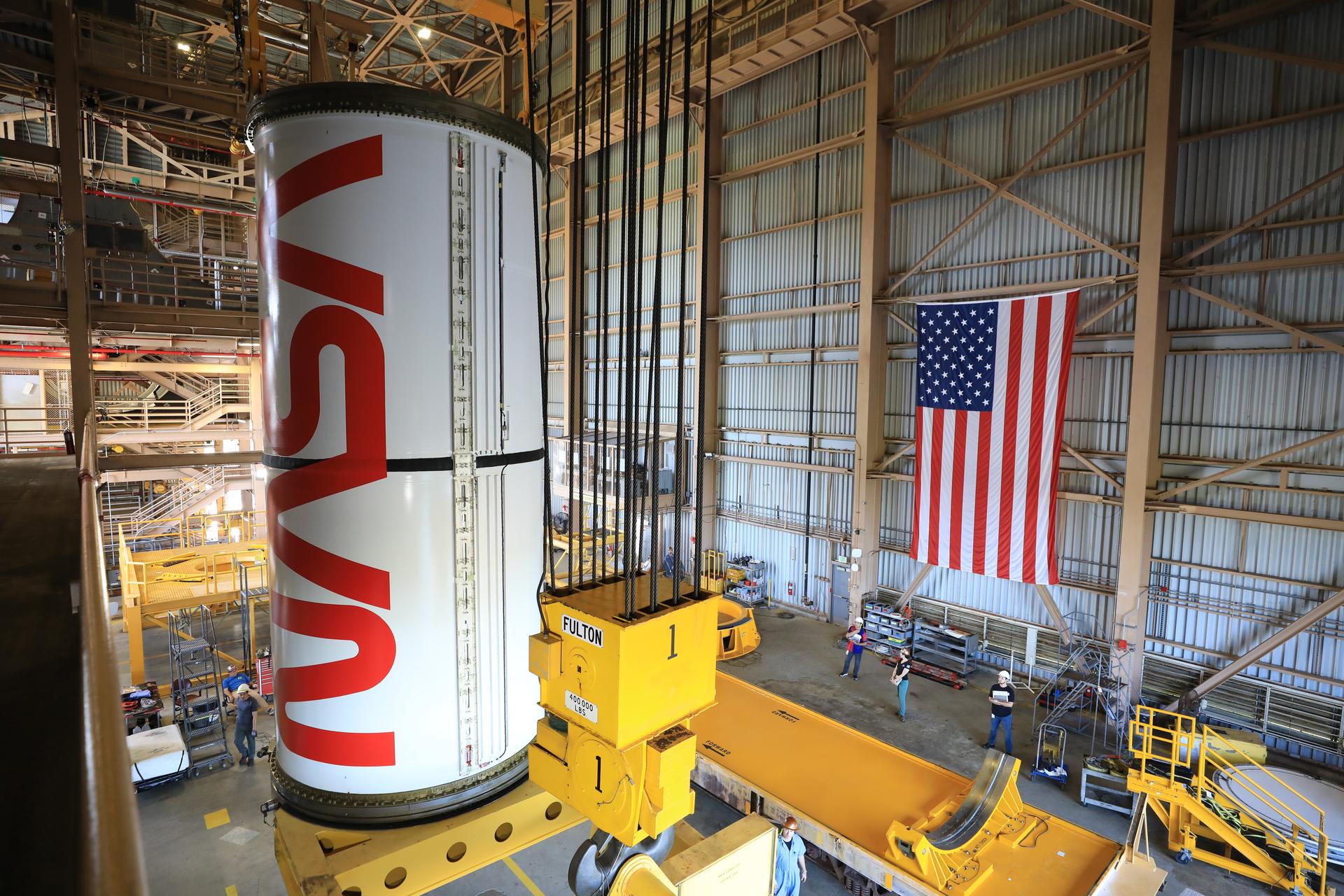 Technicians with NASA’s Exploration Ground Systems Program lift the right center center solid rocket booster, containing the NASA “worm” insignia, for the agency’s Artemis III SLS (Space Launch System) rocket onto the work stand ahead of inspection inside the Rotation, Processing and Surge Facility at the agency’s Kennedy Space Center in Florida on Wednesday, July 22, 2026. The SLS rocket’s twin boosters, manufactured by Northrop Grumman in Utah, will provide more than 75 percent of the SLS rocket’s total thrust at launch. The Artemis III mission will launch crew in the Orion spacecraft on top of the SLS rocket to test rendezvous and docking capabilities between Orion and commercial spacecraft needed to land astronauts on the Moon.