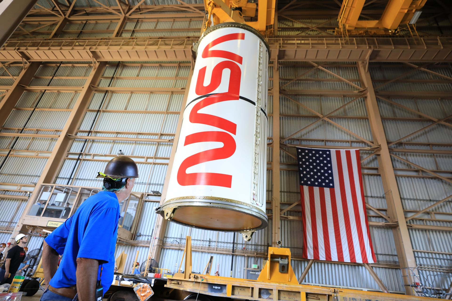 Technicians with NASA’s Exploration Ground Systems Program lift the right center center solid rocket booster, containing the NASA “worm” insignia, for the agency’s Artemis III SLS (Space Launch System) rocket onto the work stand ahead of inspection inside the Rotation, Processing and Surge Facility at the agency’s Kennedy Space Center in Florida on Wednesday, July 22, 2026. The SLS rocket’s twin boosters, manufactured by Northrop Grumman in Utah, will provide more than 75 percent of the SLS rocket’s total thrust at launch. The Artemis III mission will launch crew in the Orion spacecraft on top of the SLS rocket to test rendezvous and docking capabilities between Orion and commercial spacecraft needed to land astronauts on the Moon.