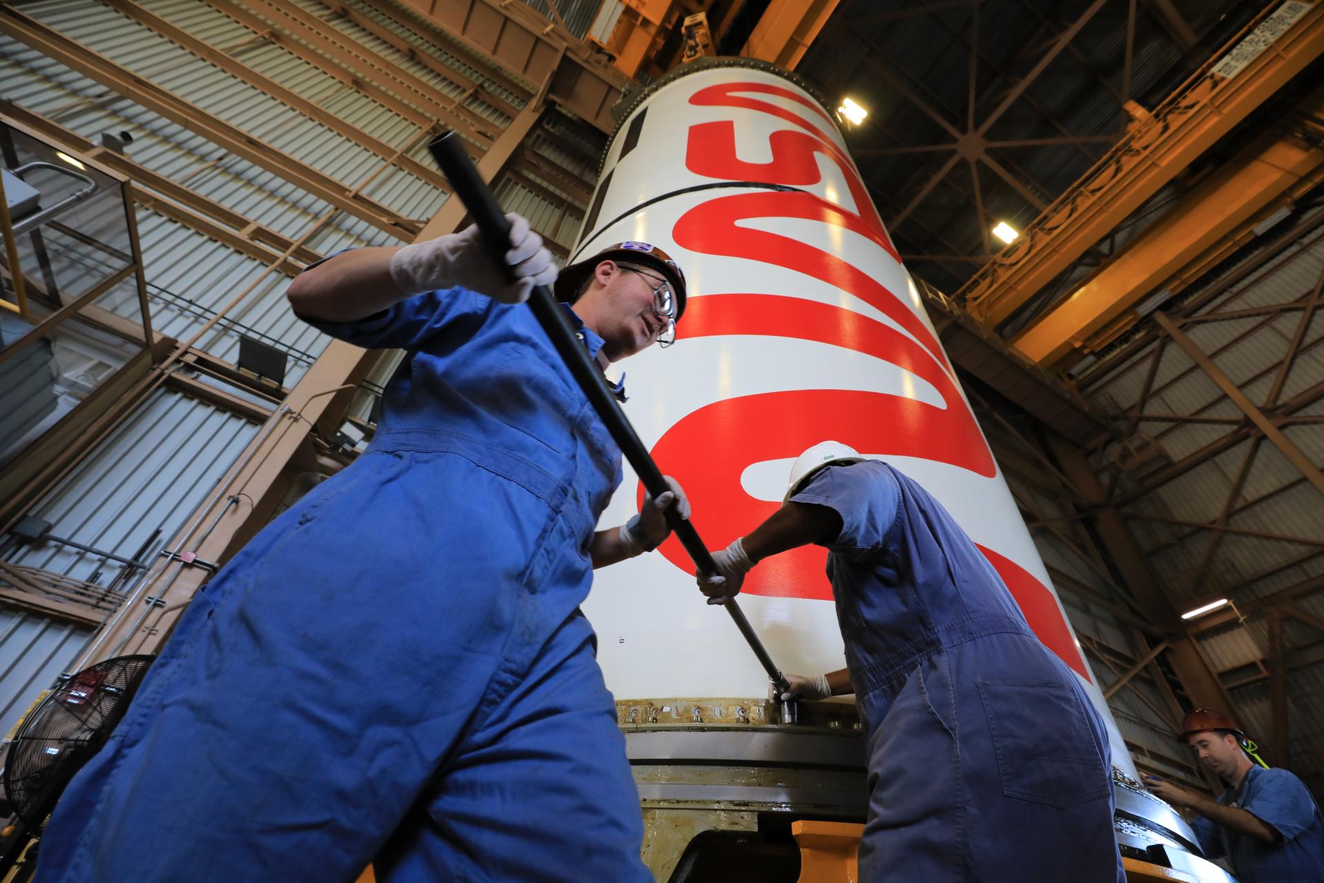 Technicians with NASA’s Exploration Ground Systems Program secure the right center center solid rocket booster, containing the NASA “worm” insignia, for the agency’s Artemis III SLS (Space Launch System) rocket onto the work stand ahead of inspection inside the Rotation, Processing and Surge Facility at the agency’s Kennedy Space Center in Florida on Wednesday, July 22, 2026. The SLS rocket’s twin boosters, manufactured by Northrop Grumman in Utah, will provide more than 75 percent of the SLS rocket’s total thrust at launch. The Artemis III mission will launch crew in the Orion spacecraft on top of the SLS rocket to test rendezvous and docking capabilities between Orion and commercial spacecraft needed to land astronauts on the Moon.