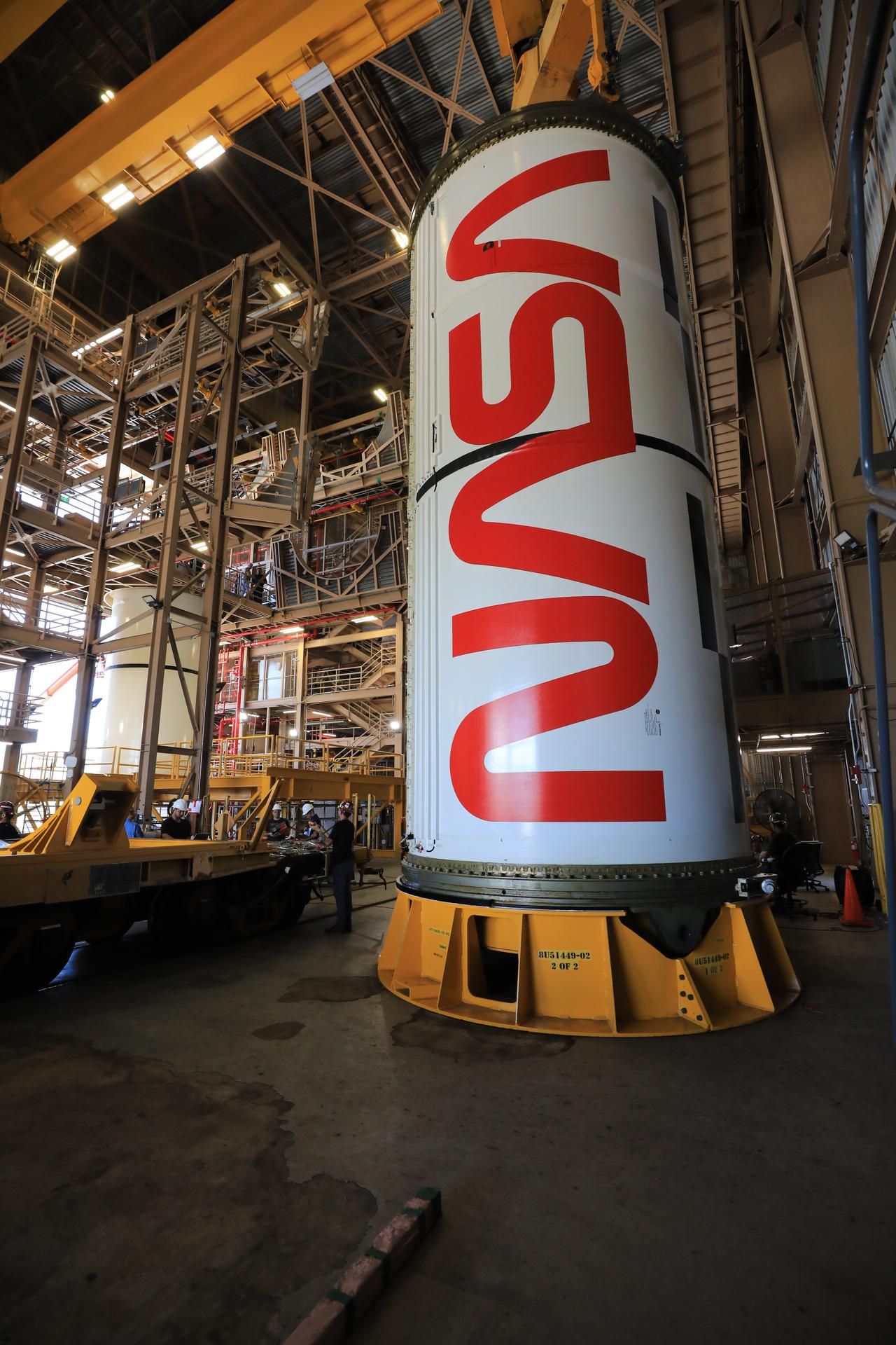 The right center center solid rocket booster segment, containing the NASA “worm” insignia, for the agency’s Artemis III SLS (Space Launch System) rocket undergoes processing, with the left center center solid rocket booster segment visible in the background, inside the Rotation, Processing and Surge Facility at the agency’s Kennedy Space Center in Florida on Thursday, July 23, 2026. The SLS rocket’s twin boosters, manufactured by Northrop Grumman in Utah, will provide more than 75 percent of the SLS rocket’s total thrust at launch. The Artemis III mission will launch crew in the Orion spacecraft on top of the SLS rocket to test rendezvous and docking capabilities between Orion and commercial spacecraft needed to land astronauts on the Moon.