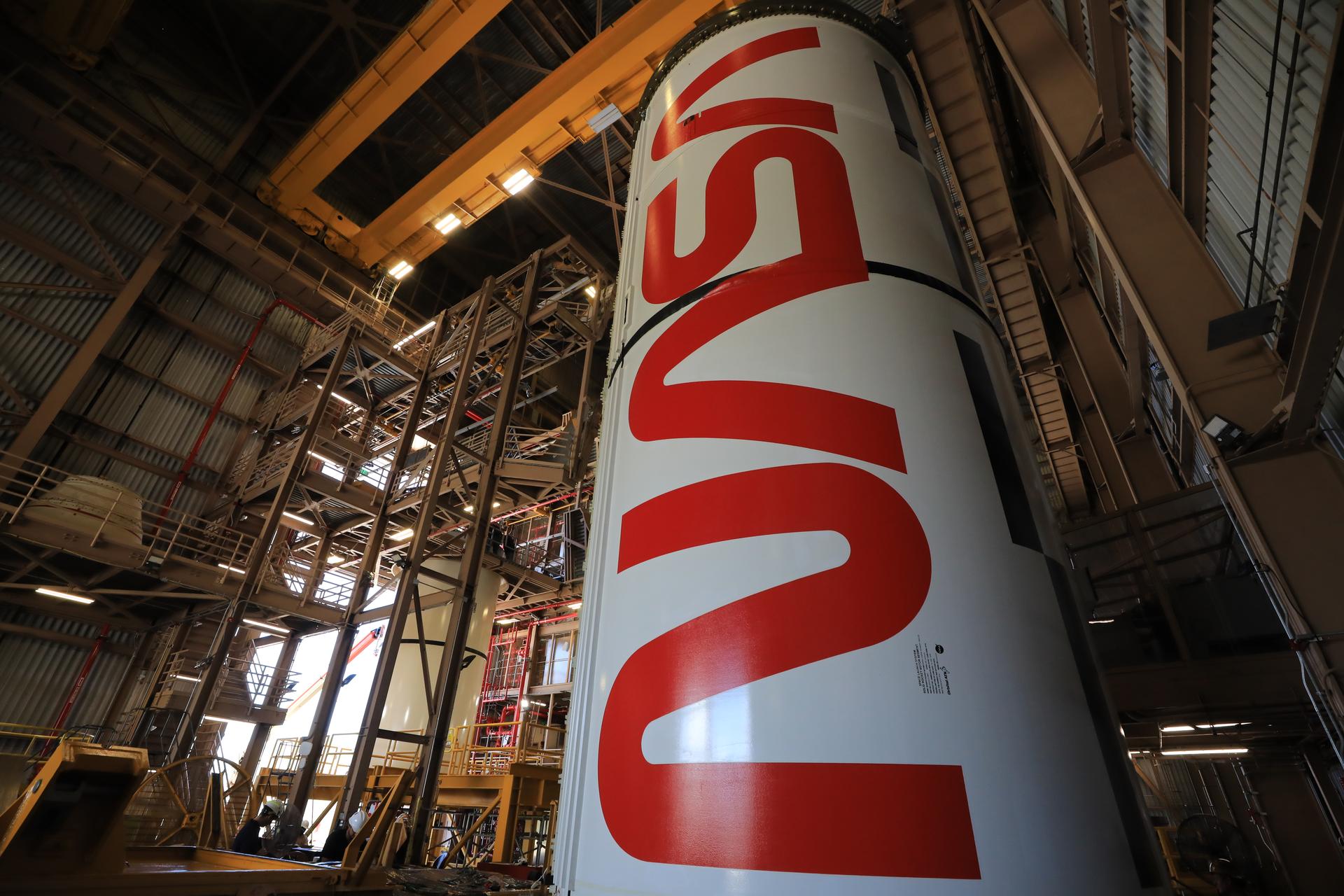 The right center center solid rocket booster segment, containing the NASA “worm” insignia, for the agency’s Artemis III SLS (Space Launch System) rocket undergoes processing, with the left center center solid rocket booster segment visible in the background, inside the Rotation, Processing and Surge Facility at the agency’s Kennedy Space Center in Florida on Thursday, July 23, 2026. The SLS rocket’s twin boosters, manufactured by Northrop Grumman in Utah, will provide more than 75 percent of the SLS rocket’s total thrust at launch. The Artemis III mission will launch crew in the Orion spacecraft on top of the SLS rocket to test rendezvous and docking capabilities between Orion and commercial spacecraft needed to land astronauts on the Moon.