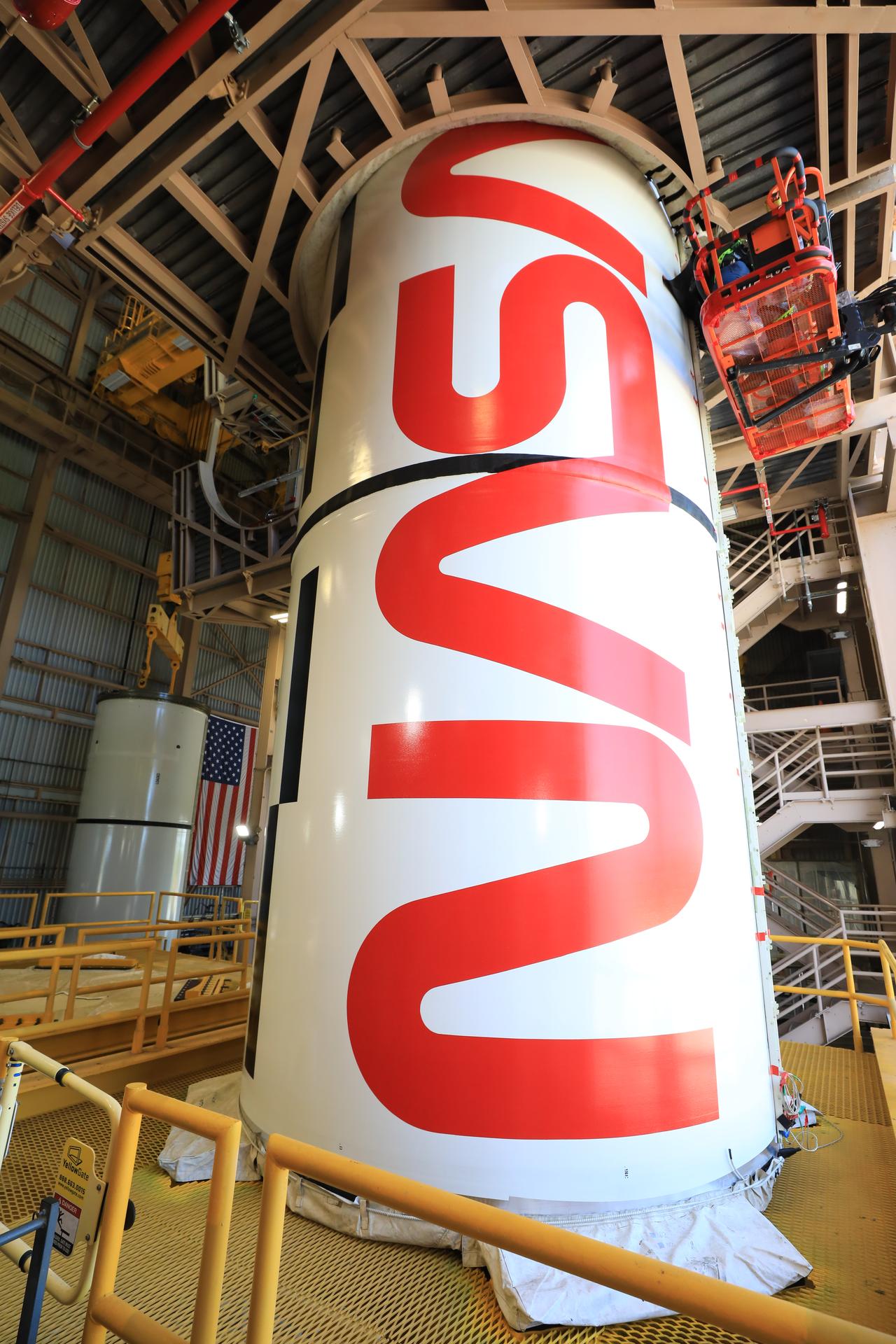 The right center center solid rocket booster segment, containing the NASA “worm” insignia, for the agency’s Artemis III SLS (Space Launch System) rocket undergoes processing, with the left center center solid rocket booster segment visible in the background, inside the Rotation, Processing and Surge Facility at the agency’s Kennedy Space Center in Florida on Thursday, July 23, 2026. The SLS rocket’s twin boosters, manufactured by Northrop Grumman in Utah, will provide more than 75 percent of the SLS rocket’s total thrust at launch. The Artemis III mission will launch crew in the Orion spacecraft on top of the SLS rocket to test rendezvous and docking capabilities between Orion and commercial spacecraft needed to land astronauts on the Moon.