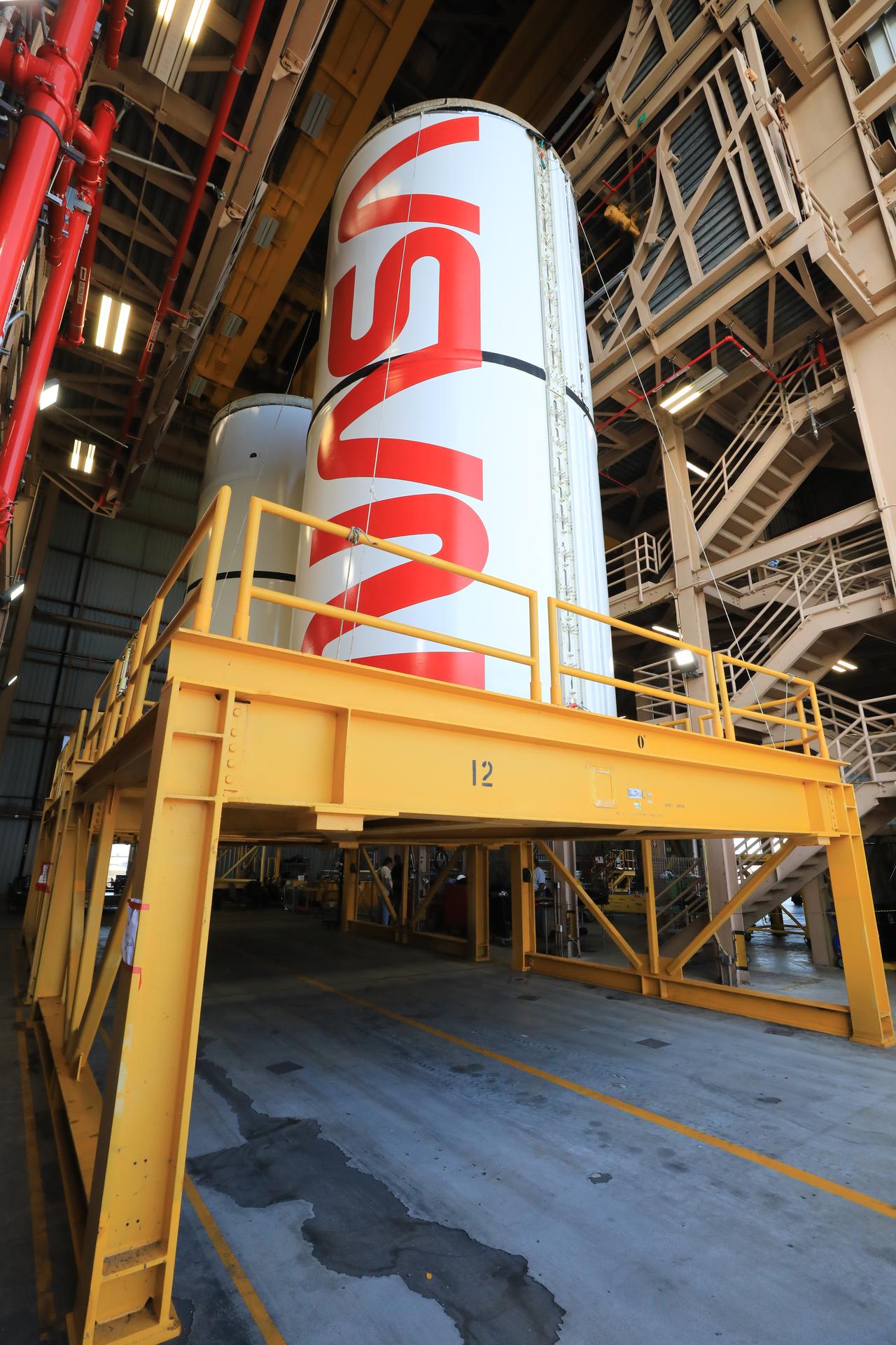 The right center center solid rocket booster segment, containing the NASA “worm” insignia, and the left center center solid rocket booster segment for the agency’s Artemis III SLS (Space Launch System) rocket undergo processing inside the Rotation, Processing and Surge Facility at the agency’s Kennedy Space Center in Florida on Friday, July 24, 2026. The SLS rocket’s twin boosters, manufactured by Northrop Grumman in Utah, will provide more than 75 percent of the SLS rocket’s total thrust at launch. The Artemis III mission will launch crew in the Orion spacecraft on top of the SLS rocket to test rendezvous and docking capabilities between Orion and commercial spacecraft needed to land astronauts on the Moon.