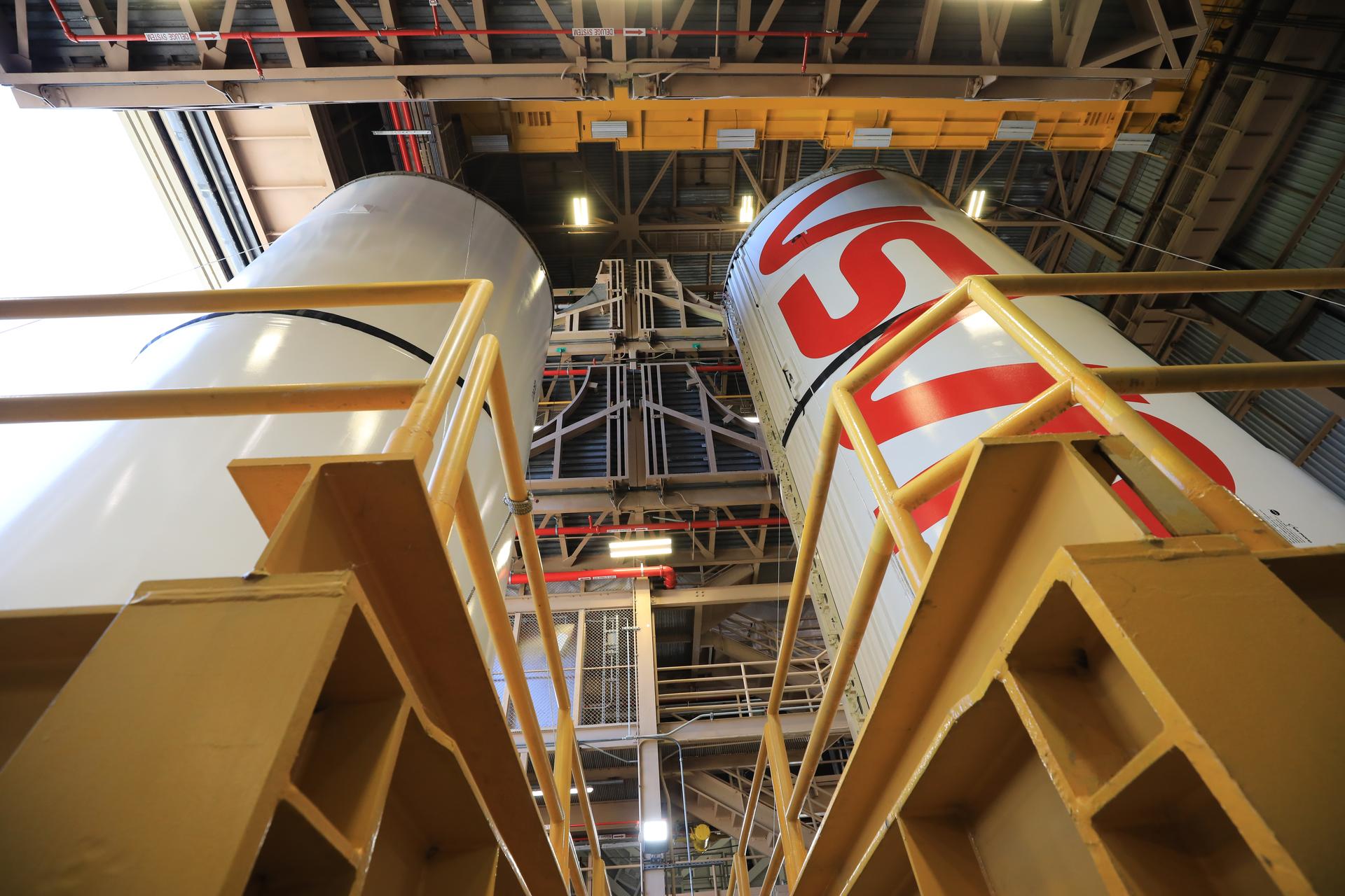 The right center center solid rocket booster segment, containing the NASA “worm” insignia, and the left center center solid rocket booster segment for the agency’s Artemis III SLS (Space Launch System) rocket undergo processing inside the Rotation, Processing and Surge Facility at the agency’s Kennedy Space Center in Florida on Friday, July 24, 2026. The SLS rocket’s twin boosters, manufactured by Northrop Grumman in Utah, will provide more than 75 percent of the SLS rocket’s total thrust at launch. The Artemis III mission will launch crew in the Orion spacecraft on top of the SLS rocket to test rendezvous and docking capabilities between Orion and commercial spacecraft needed to land astronauts on the Moon.