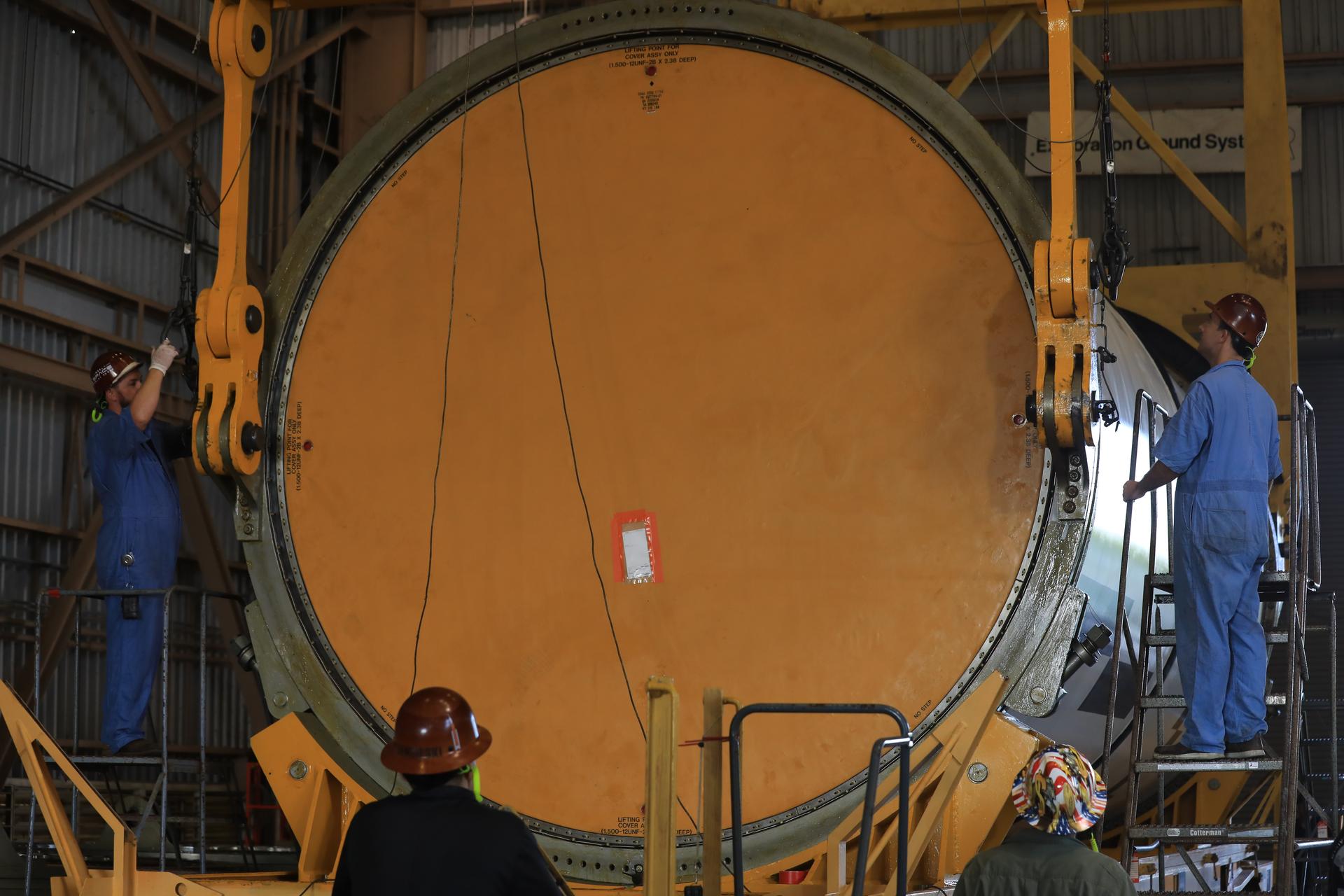 Technicians use a massive crane to rotate and lift the right-hand aft center assembly solid rocket booster segment for NASA’s Artemis III SLS (Space Launch System) rocket onto a work stand at the Rotation, Processing, and Surge Facility at the agency’s Kennedy Space Center in Florida on Wednesday, July 29, 2026. The twin boosters, comprising five segments each manufactured by Northrop Grumman in Utah, will provide more than 75 percent of the SLS rocket’s total thrust at launch. The Artemis III mission will launch crew in the Orion spacecraft on top of the SLS rocket to test rendezvous and docking capabilities between Orion and commercial spacecraft needed to land astronauts on the Moon.