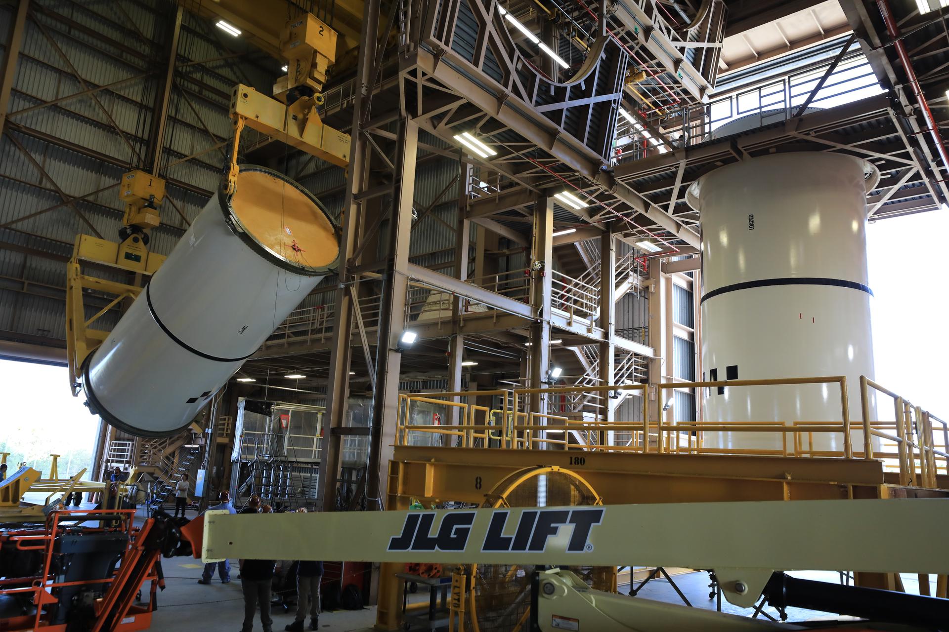 Technicians use a massive crane to rotate and lift the right-hand aft center assembly solid rocket booster segment for NASA’s Artemis III SLS (Space Launch System) rocket onto a work stand at the Rotation, Processing, and Surge Facility at the agency’s Kennedy Space Center in Florida on Wednesday, July 29, 2026, with the left-hand aft center assembly already vertical on its work stand. The twin boosters, comprising five segments each manufactured by Northrop Grumman in Utah, will provide more than 75 percent of the SLS rocket’s total thrust at launch. The Artemis III mission will launch crew in the Orion spacecraft on top of the SLS rocket to test rendezvous and docking capabilities between Orion and commercial spacecraft needed to land astronauts on the Moon.